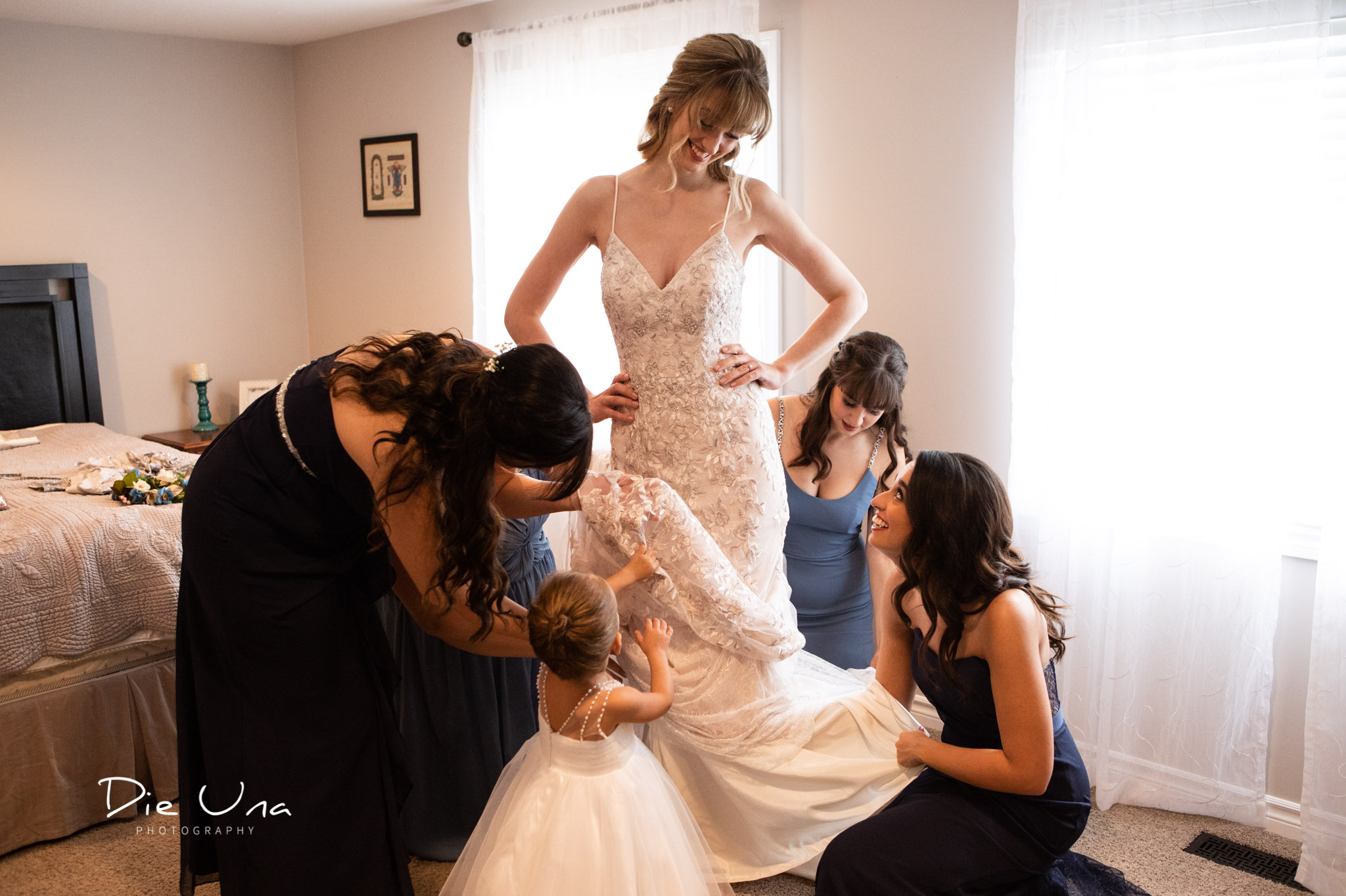 all the bridesmaids and flower girl helping the bride get her wedding dress on.jpg
