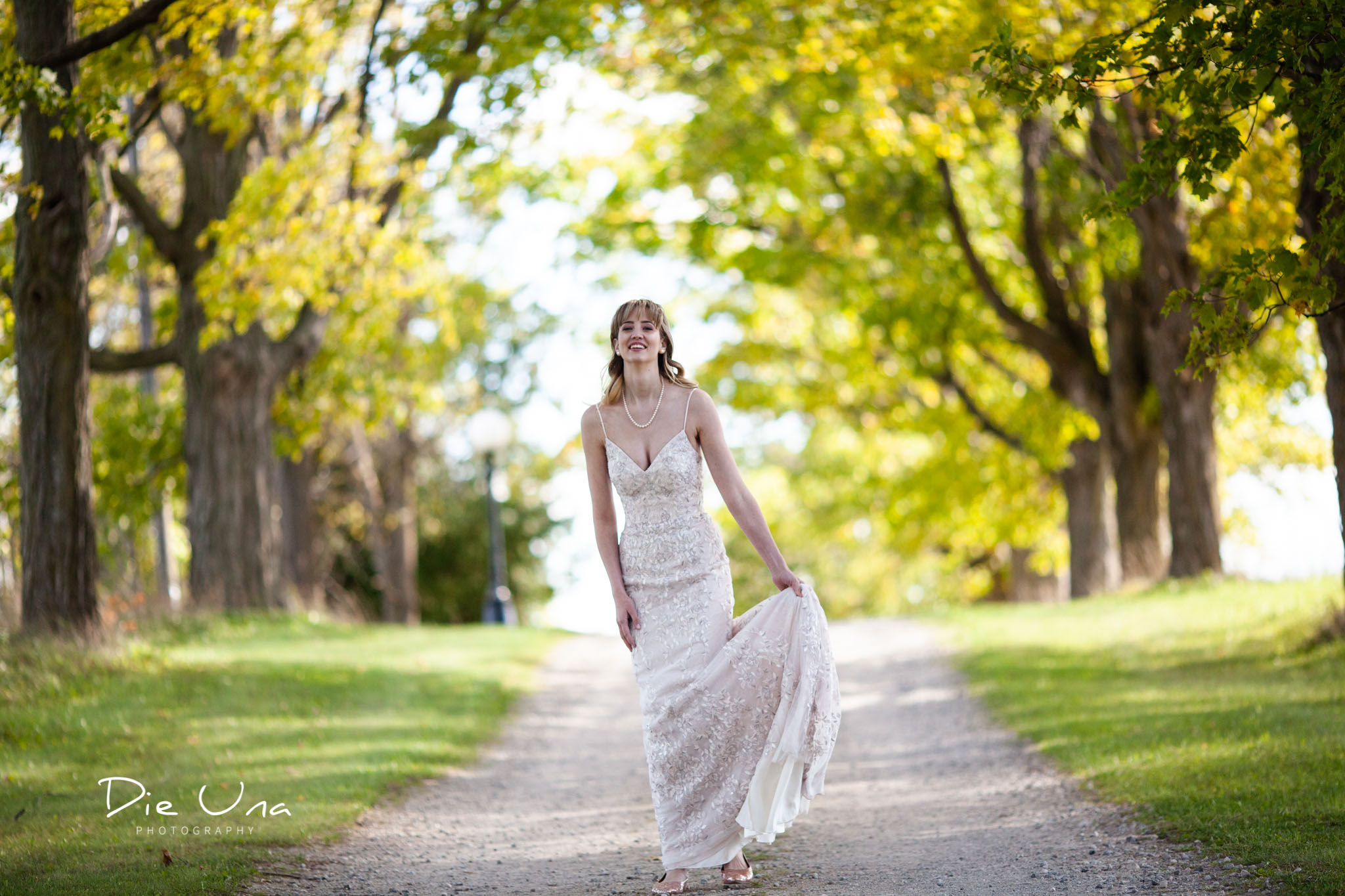 bride twirling wedding dress on tree lined driveway for wedding portraits.jpg