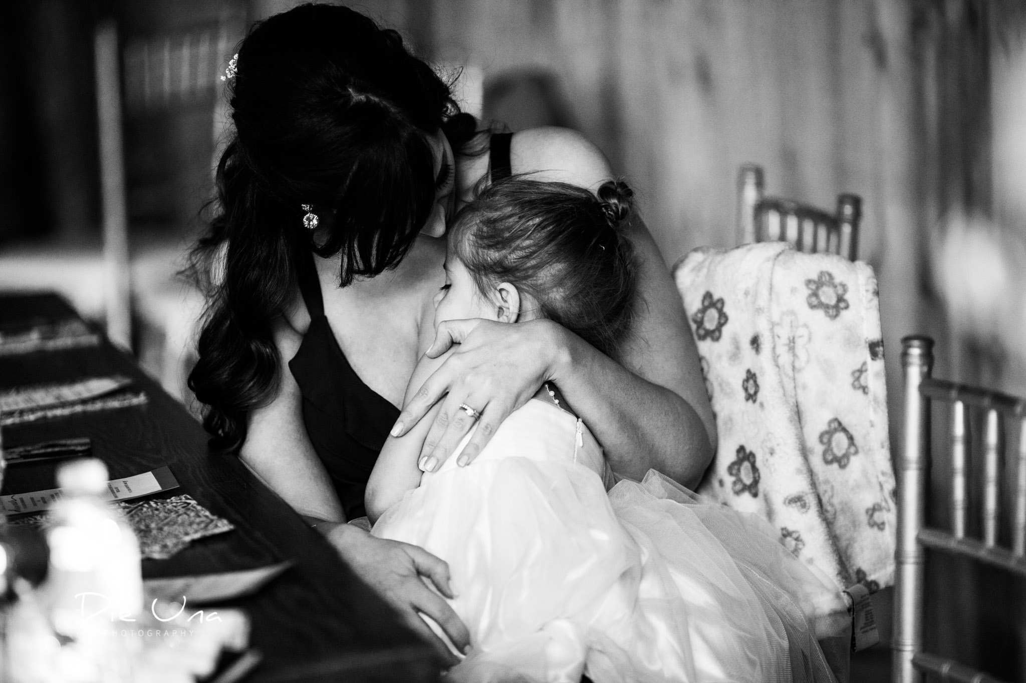 flower girl being hugged by her mom during wedding reception black and white wedding photography.jpg