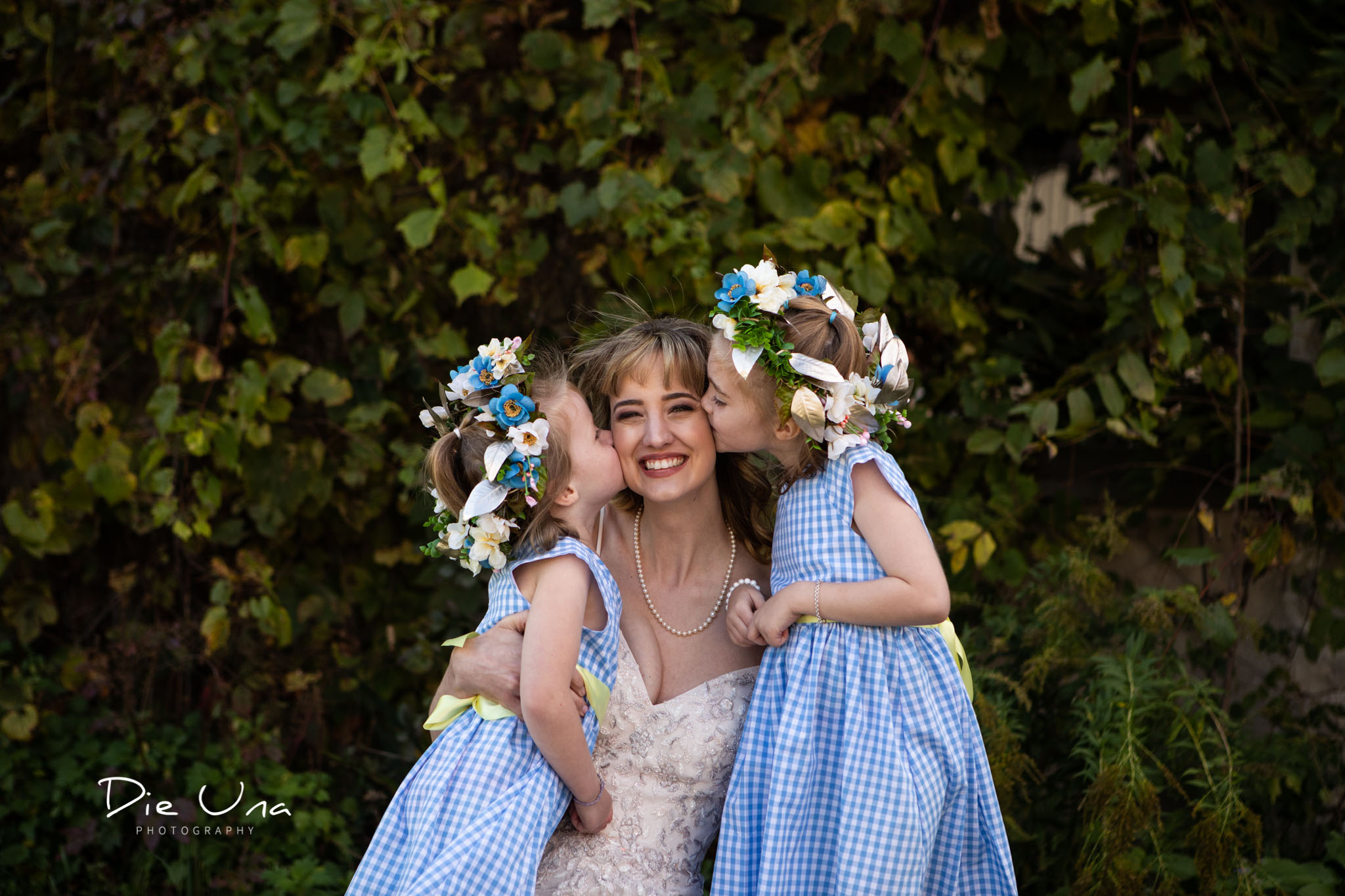 flower girls wearing blue dresses give bride a kiss on each cheek.jpg