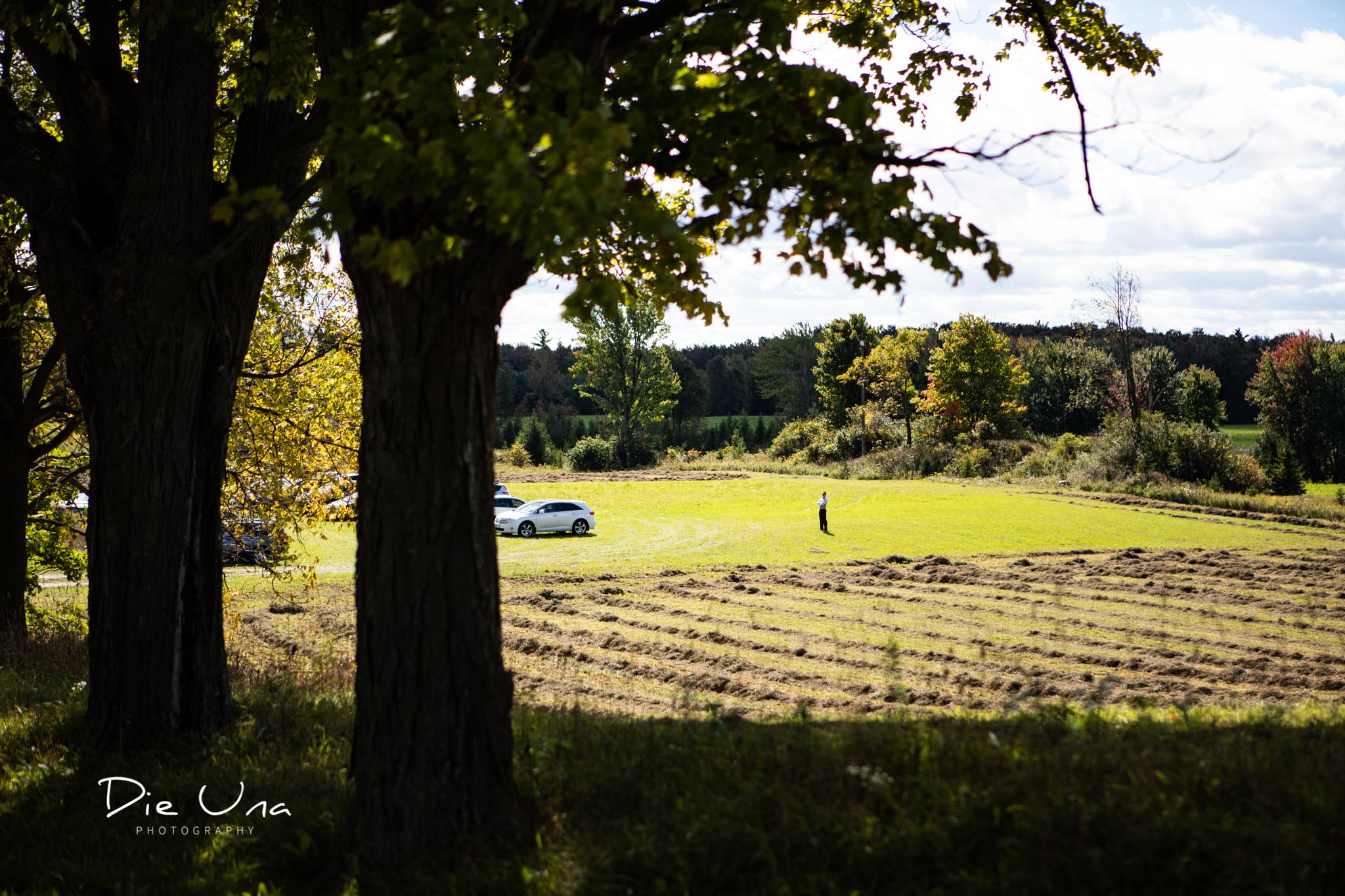 groomsman standing in field directing guests where to park their cars.jpg