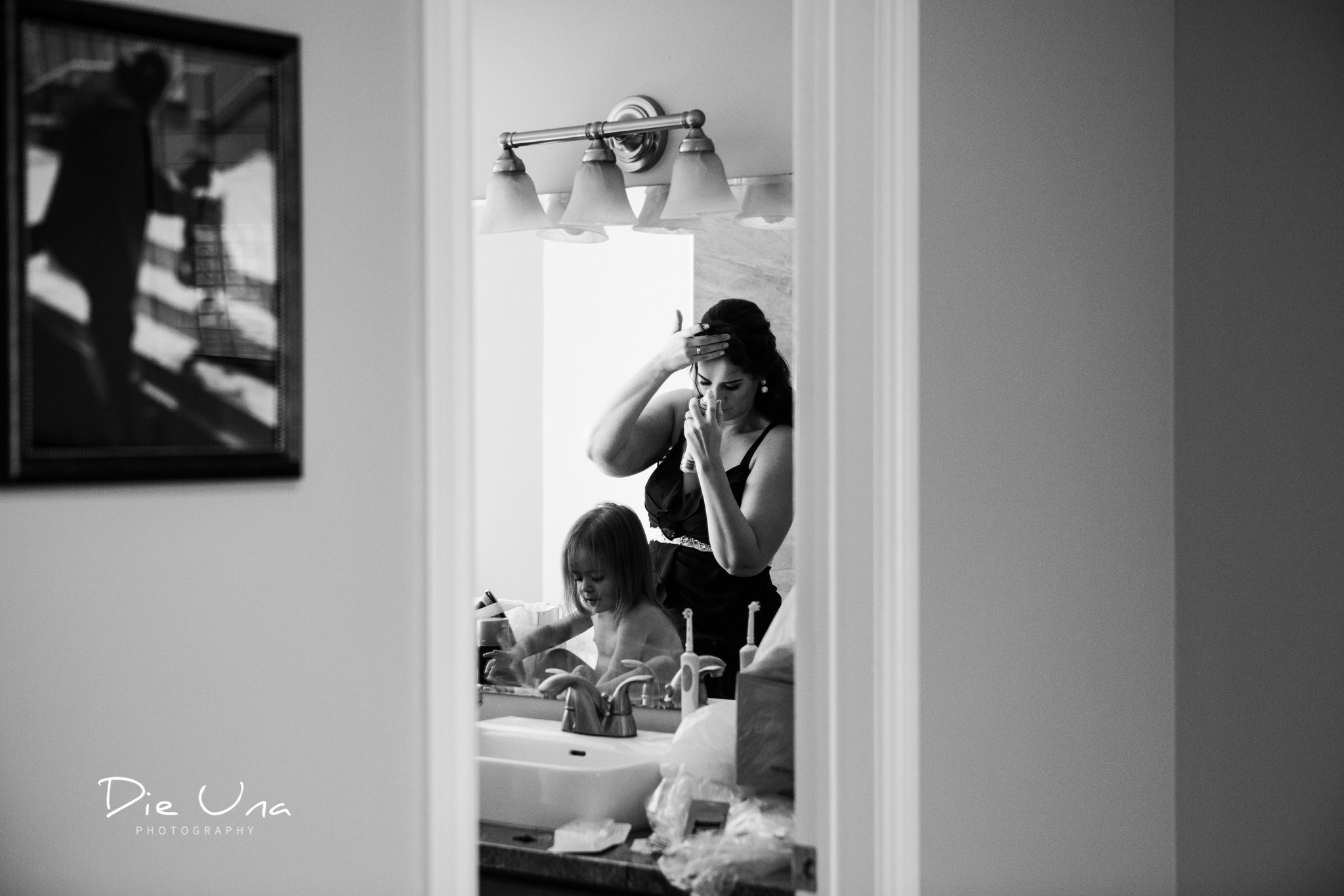 maid of honour putting on finishing touches for hair reflected in bathroom mirror with flower girl.jpg