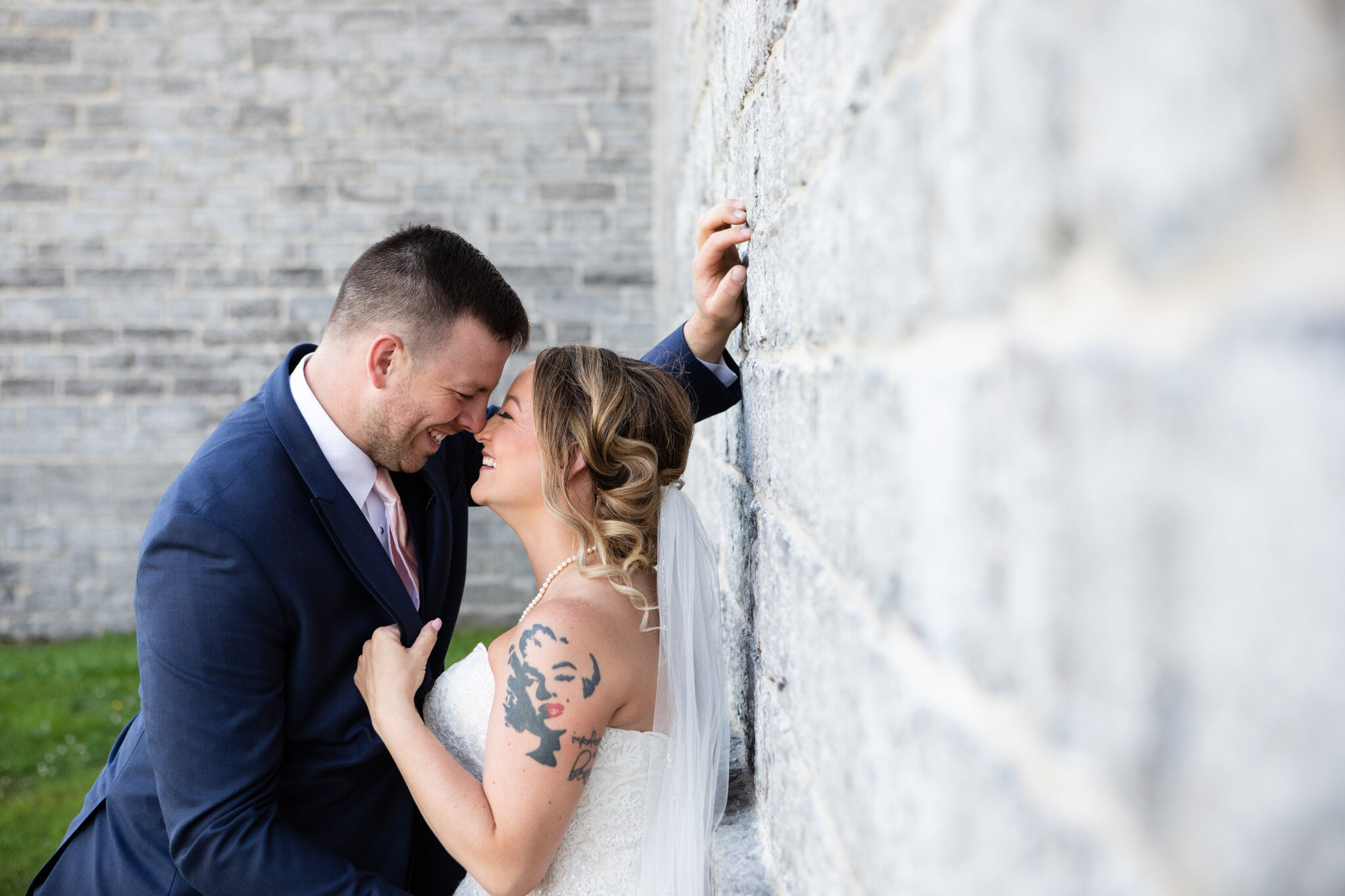 bride and groom leaning against stone wall about to kiss at St Raphael's Ruins.jpg
