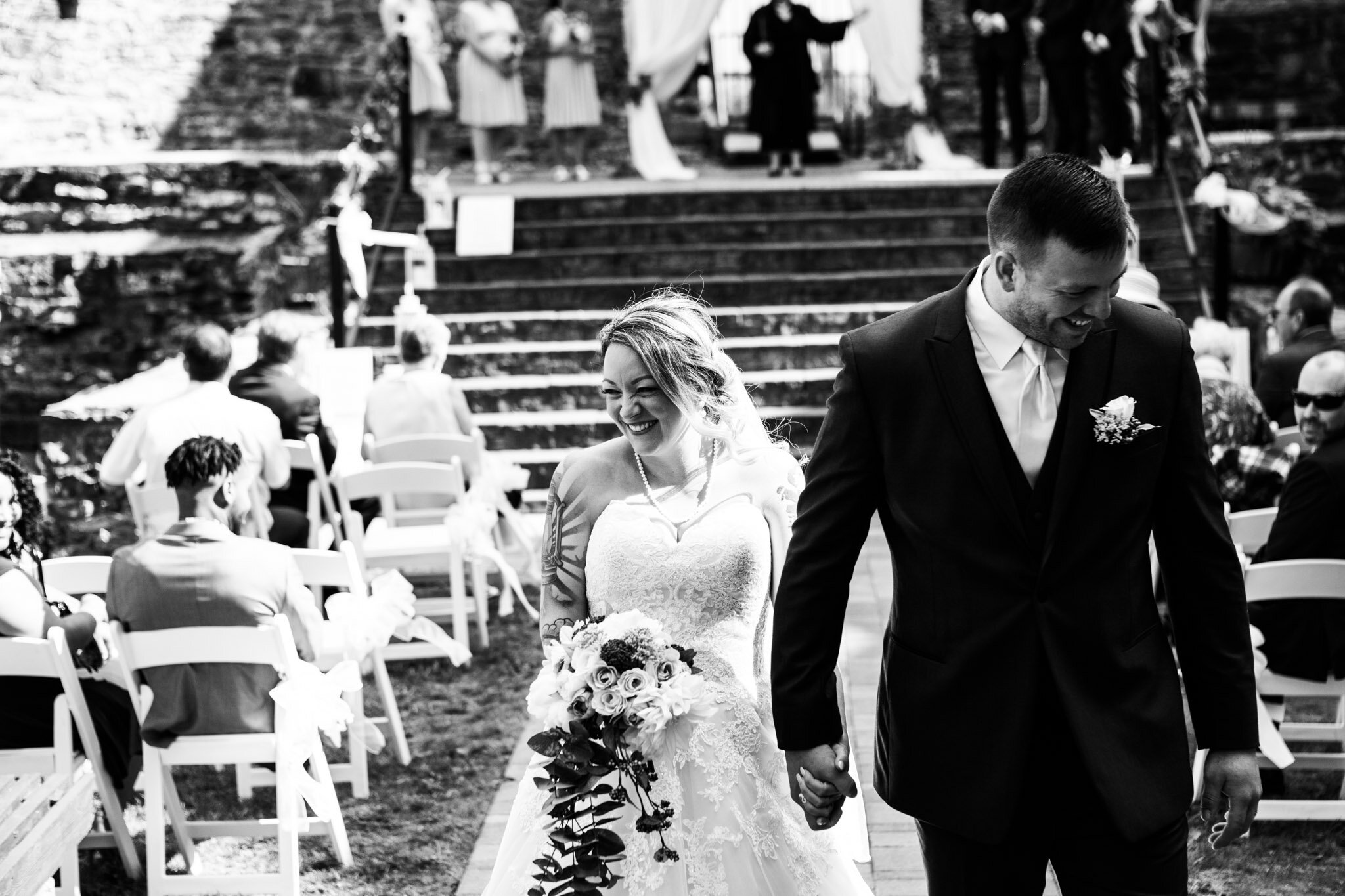 bride and groom recessional walk in St Raphael's Ruins in black and white.jpg