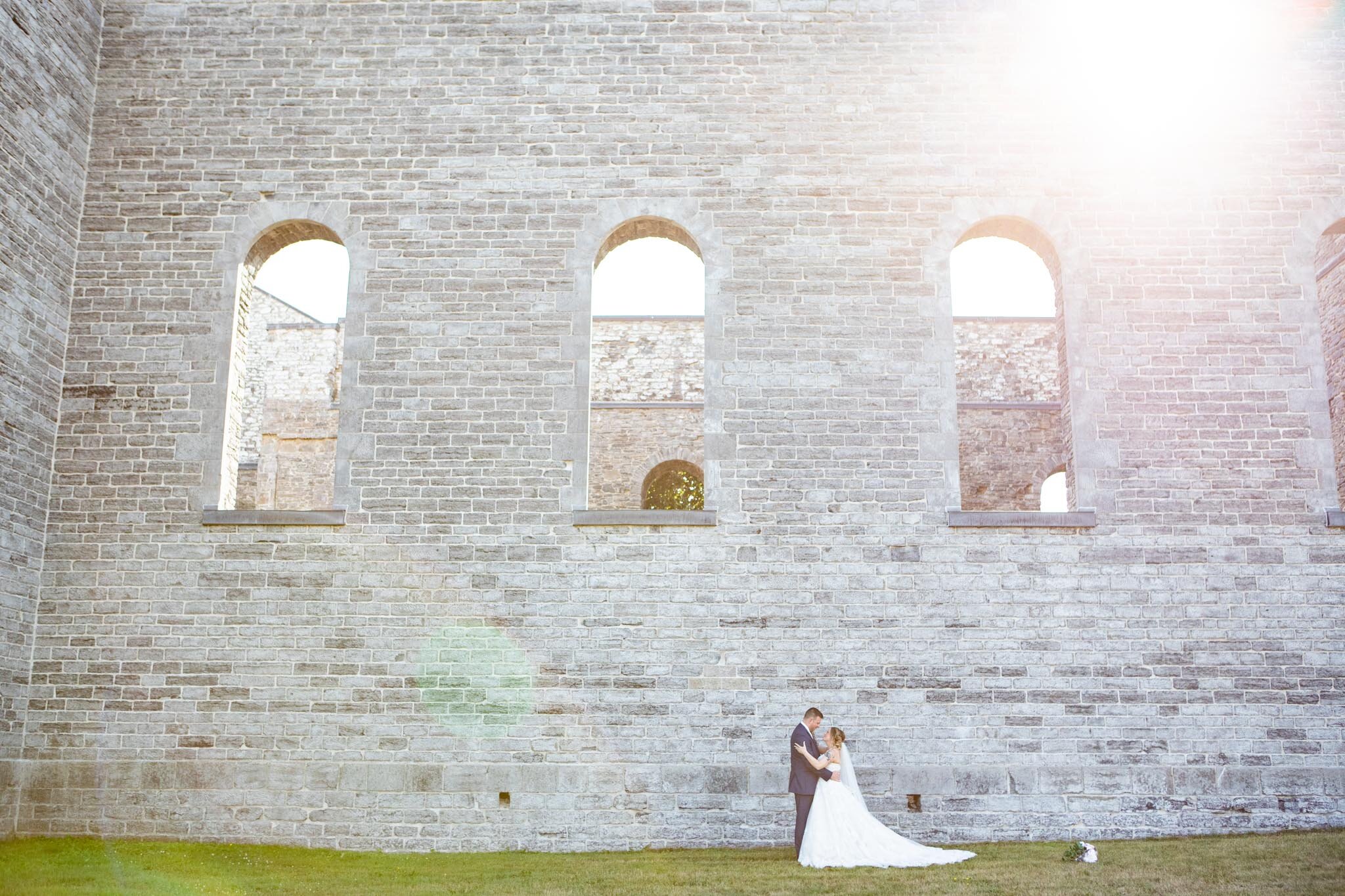 bride and groom looking at each other with entire wall of St Raphael's ruins for scale.jpg