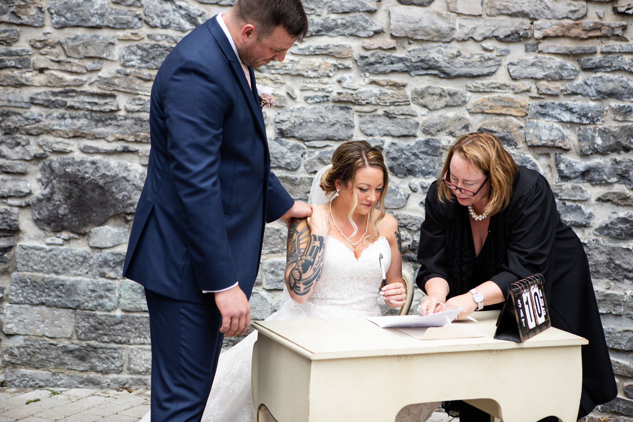 bride and groom signing marriage licence on vintage white table in St Raphael's Ruins.jpg