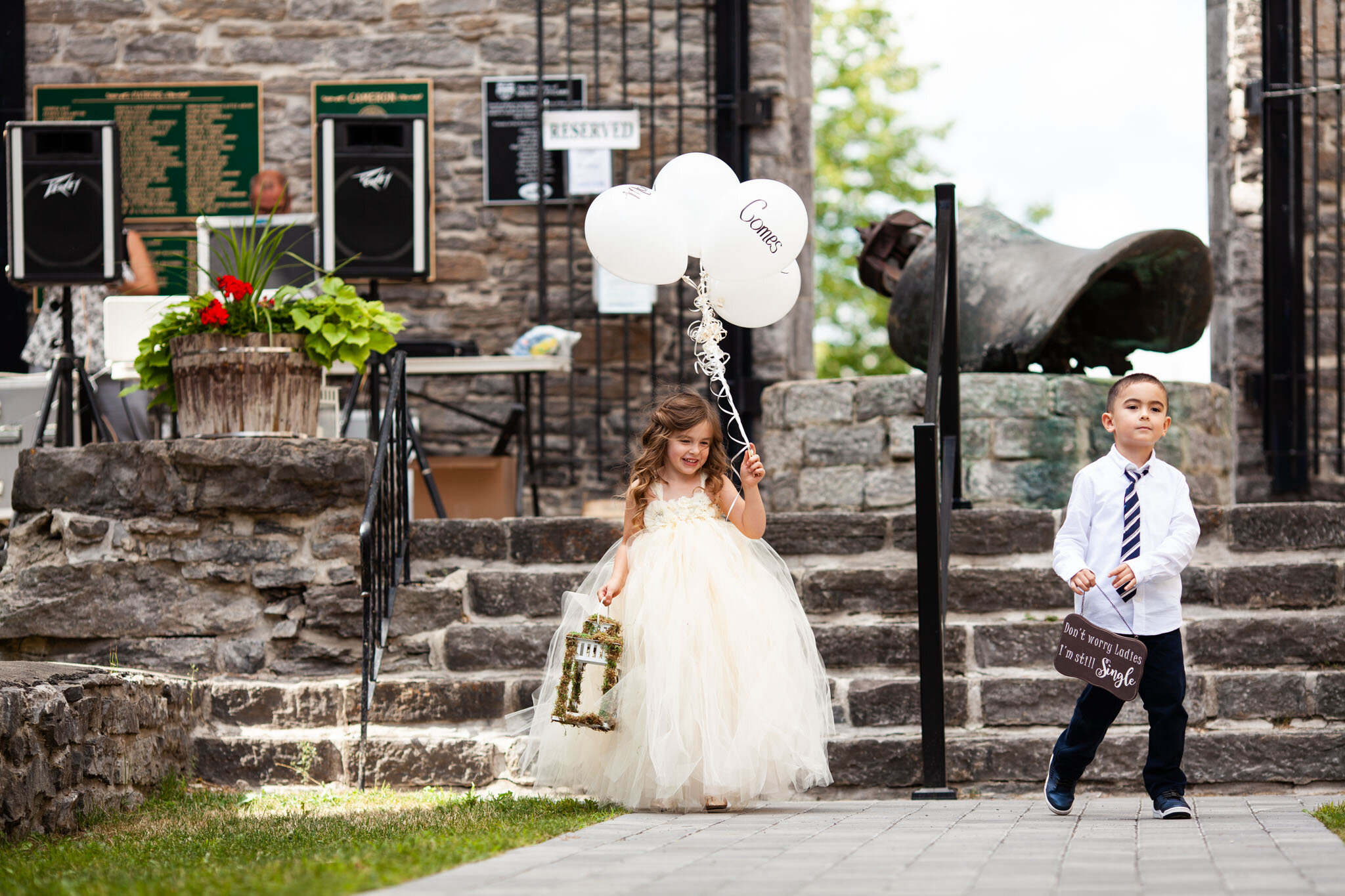 flower girl with white balloons and ring bearer walking down the aisle at St Raphael's Ruins.jpg