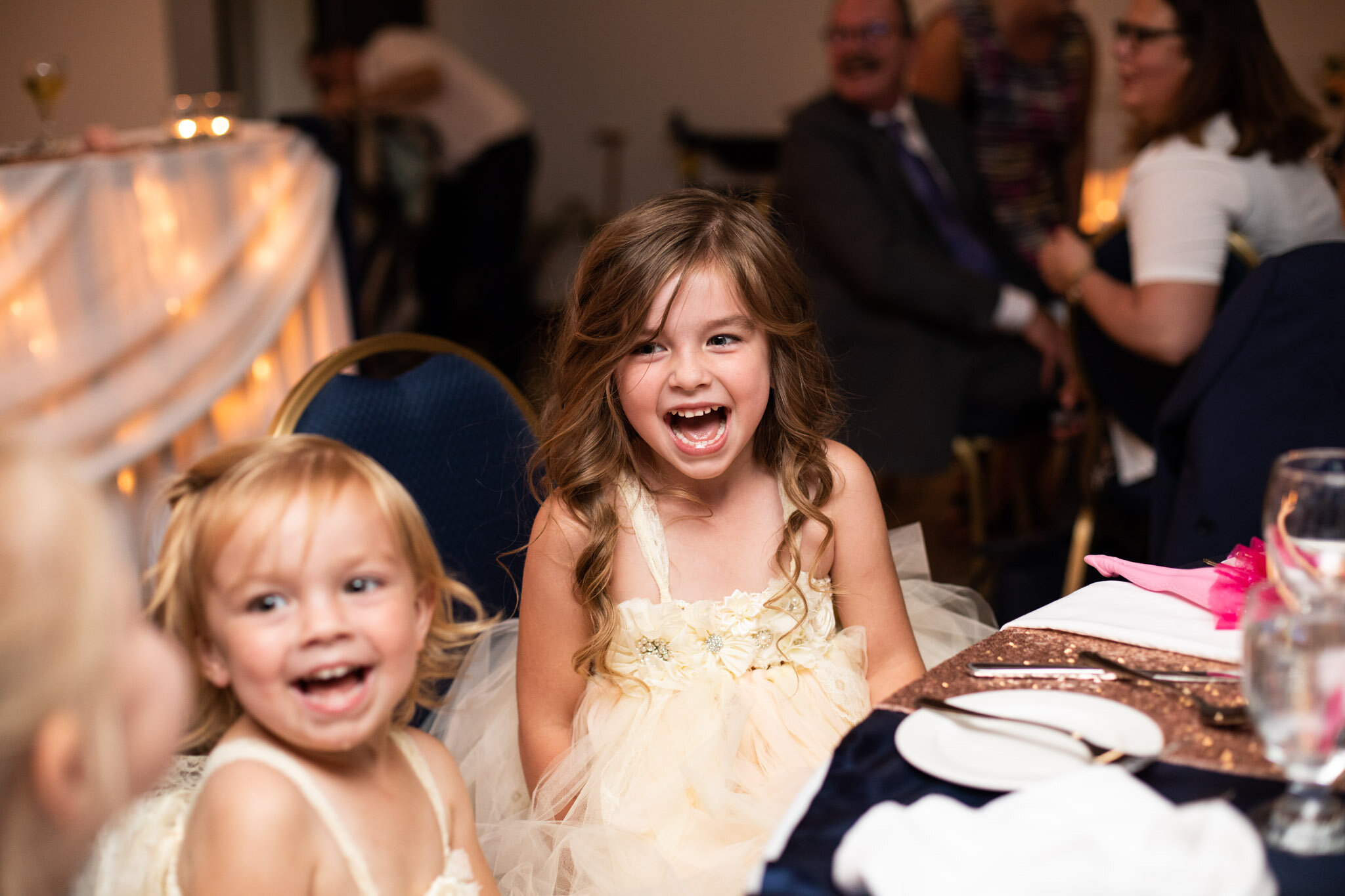 flower girls excited at wedding table during reception.jpg