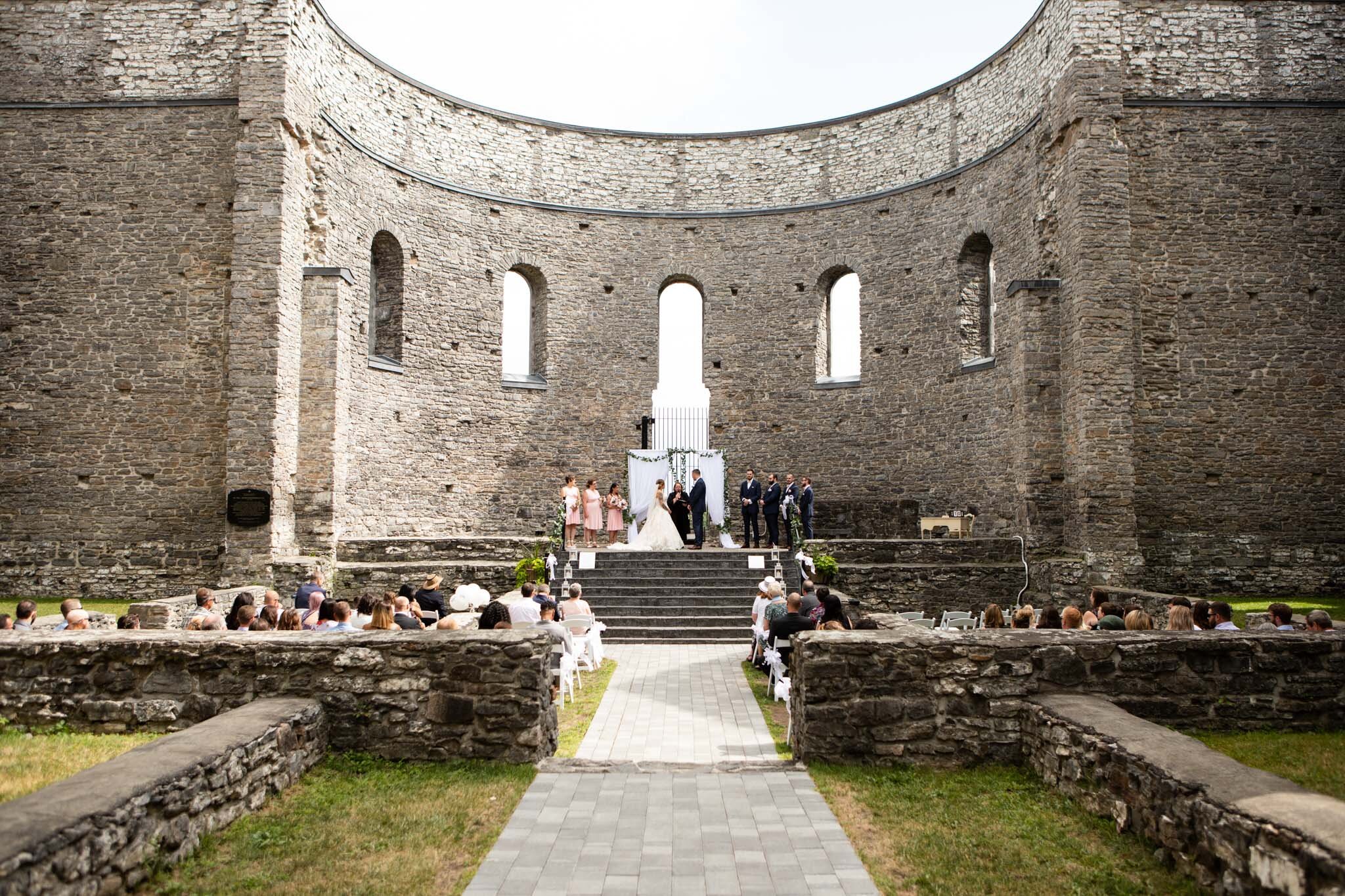 wedding party and all guests during the ceremony in St Raphael's Ruins.jpg