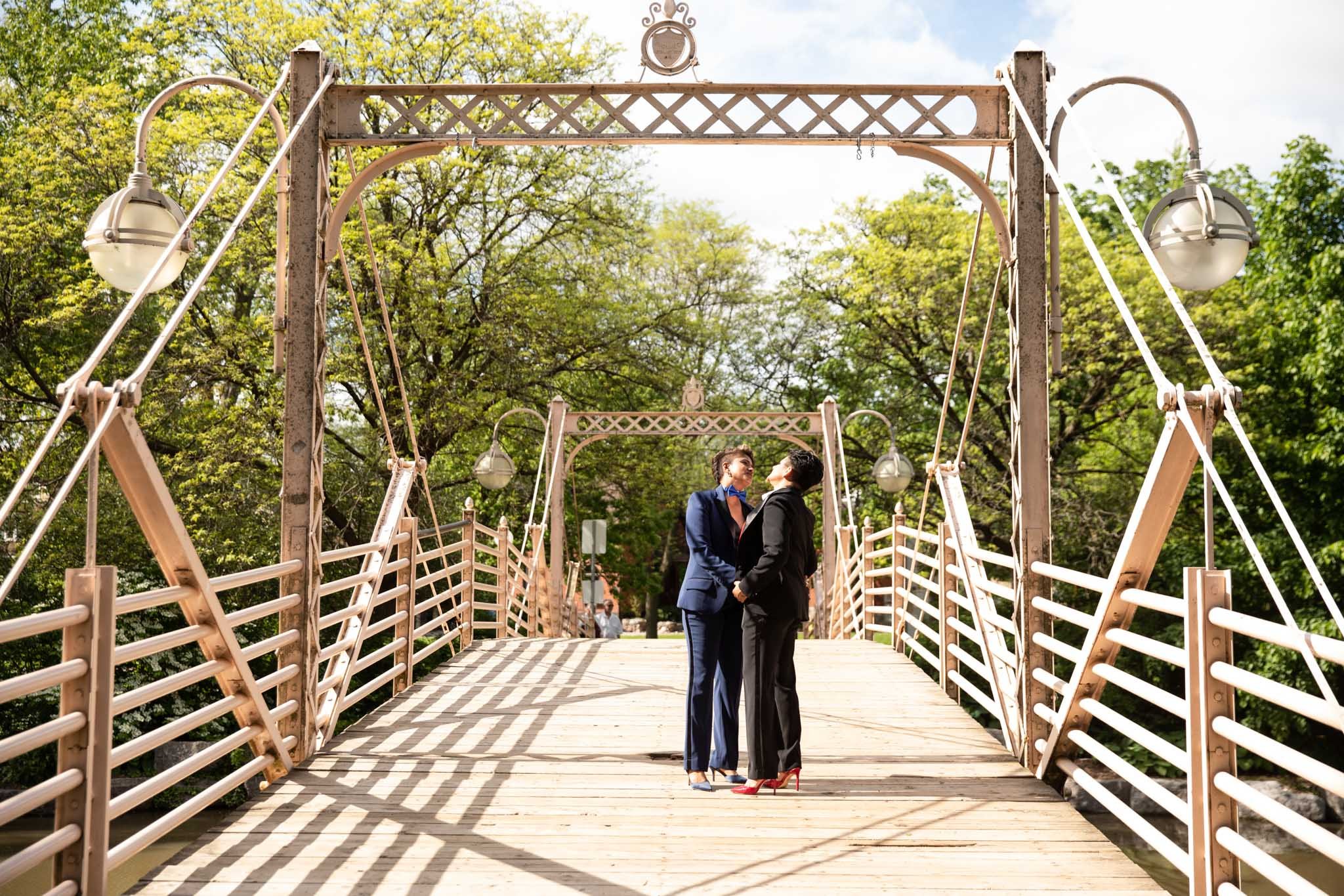 brides standing in their wedding suits standing on the bridge in Victoria Park Kitchener Ontario.jpg