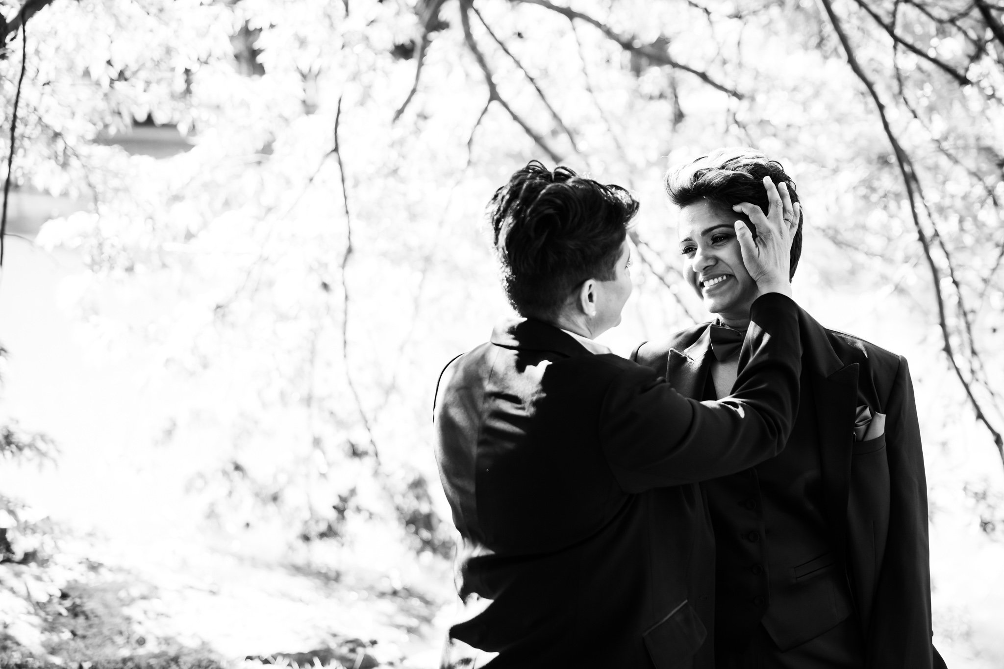 outdoor wedding image couple facing each other one partner fixing the others hair black and white.jpg