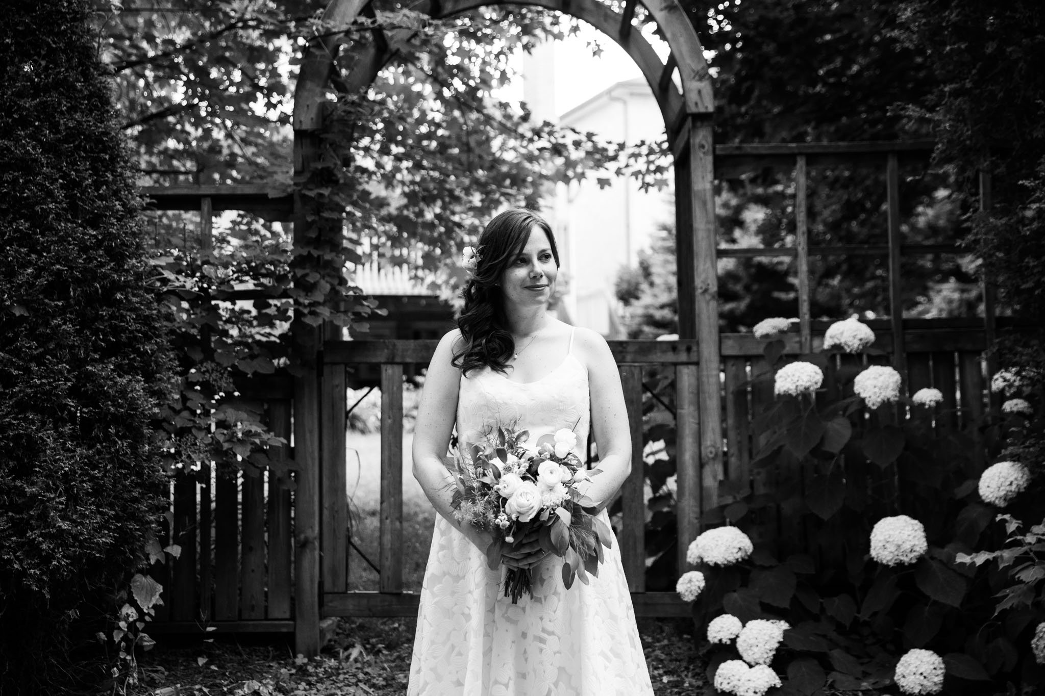 black and white picture of bride framed in an arbor with flowers.jpg