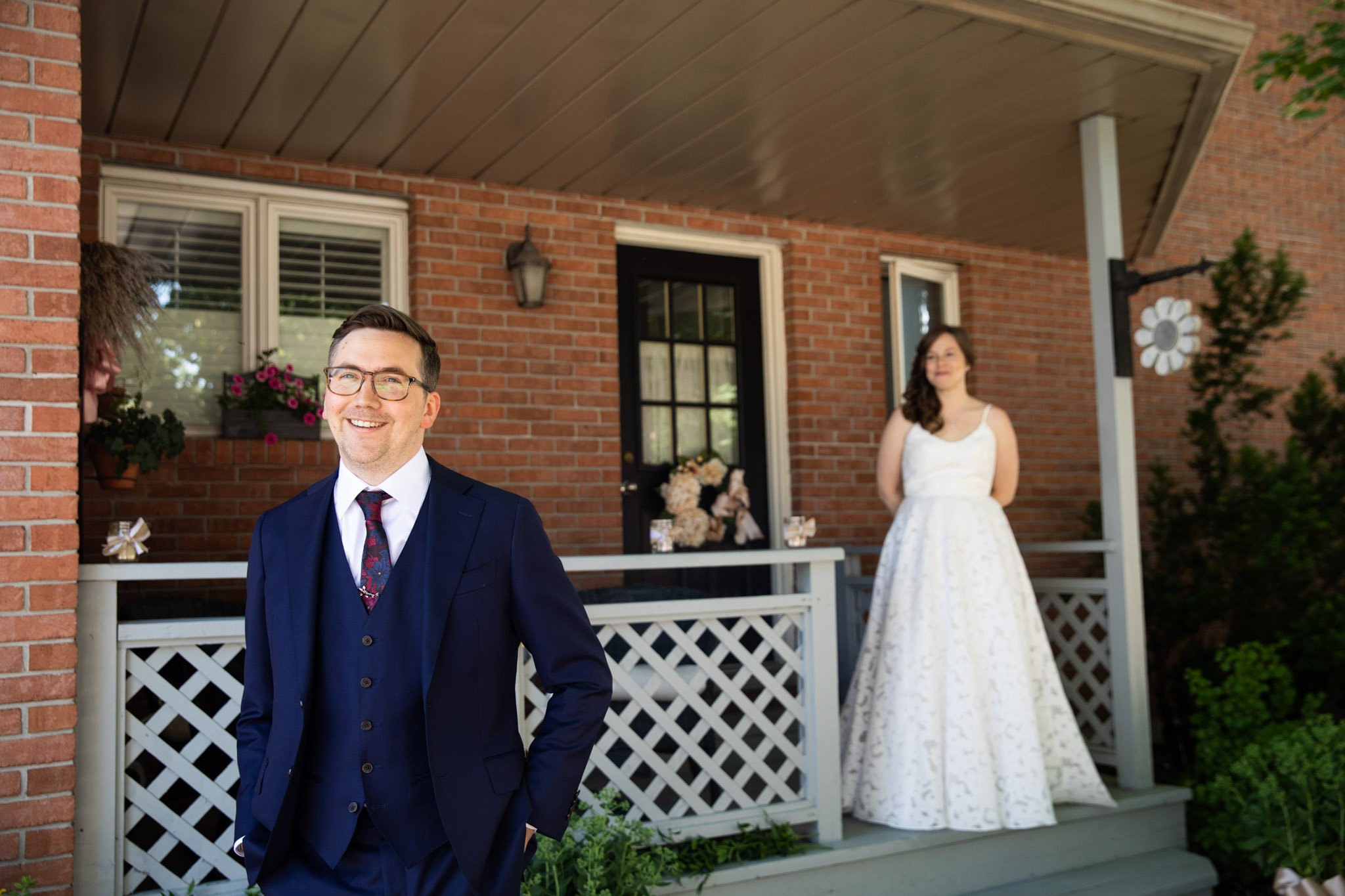 bride and groom doing a first look in front of a red brick house.jpg