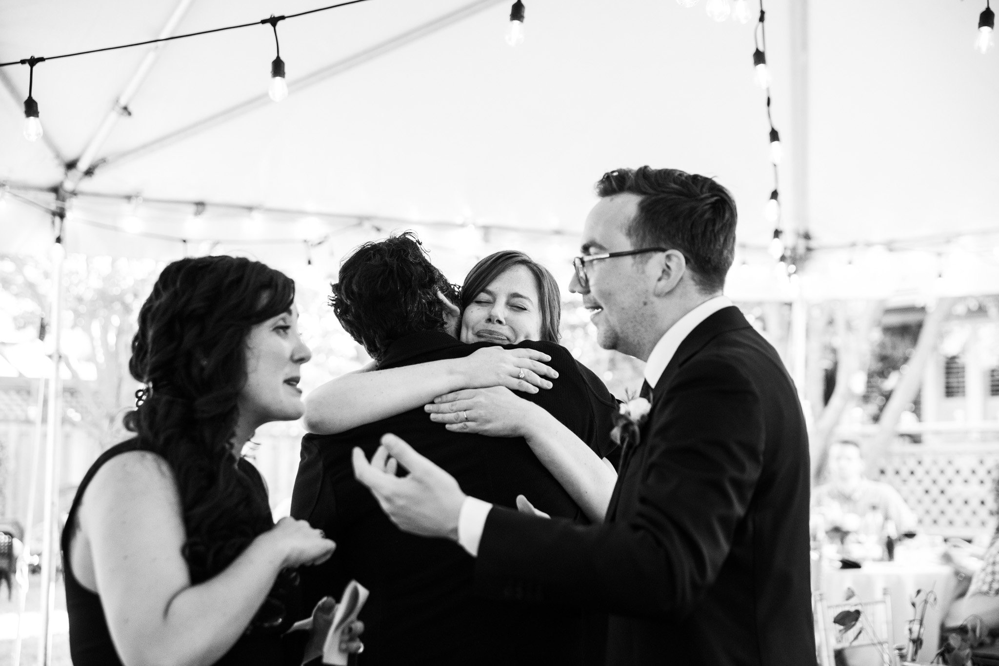 bride and groom hugging friends - black and white wedding photography.jpg