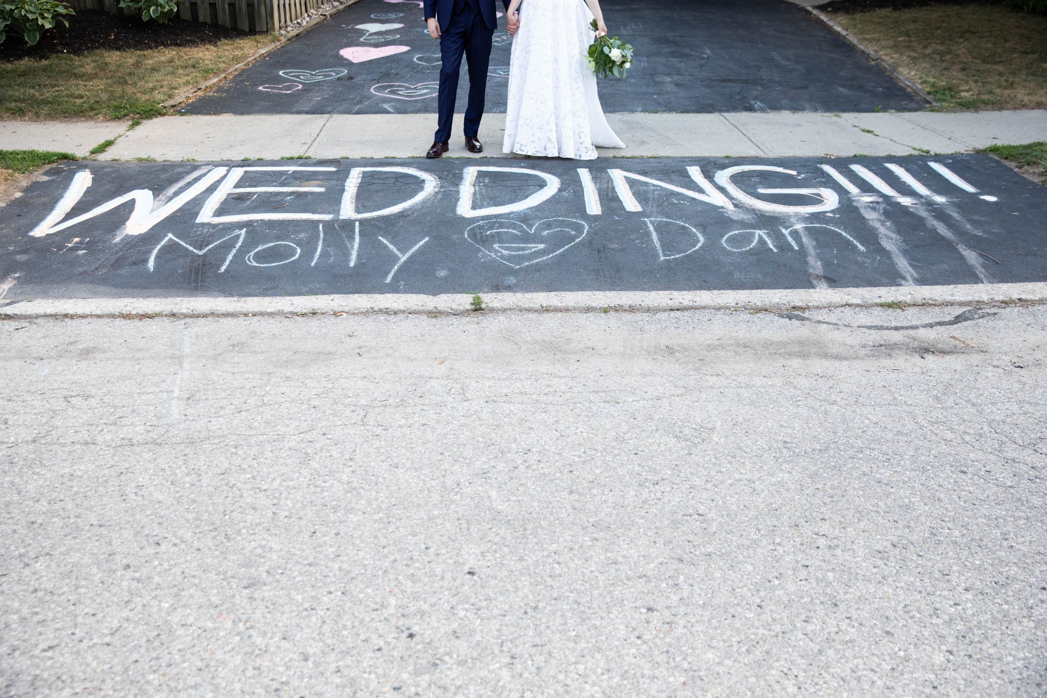 sidewalk chalk saying wedding!! with bride and groom feet at the top of the image.jpg