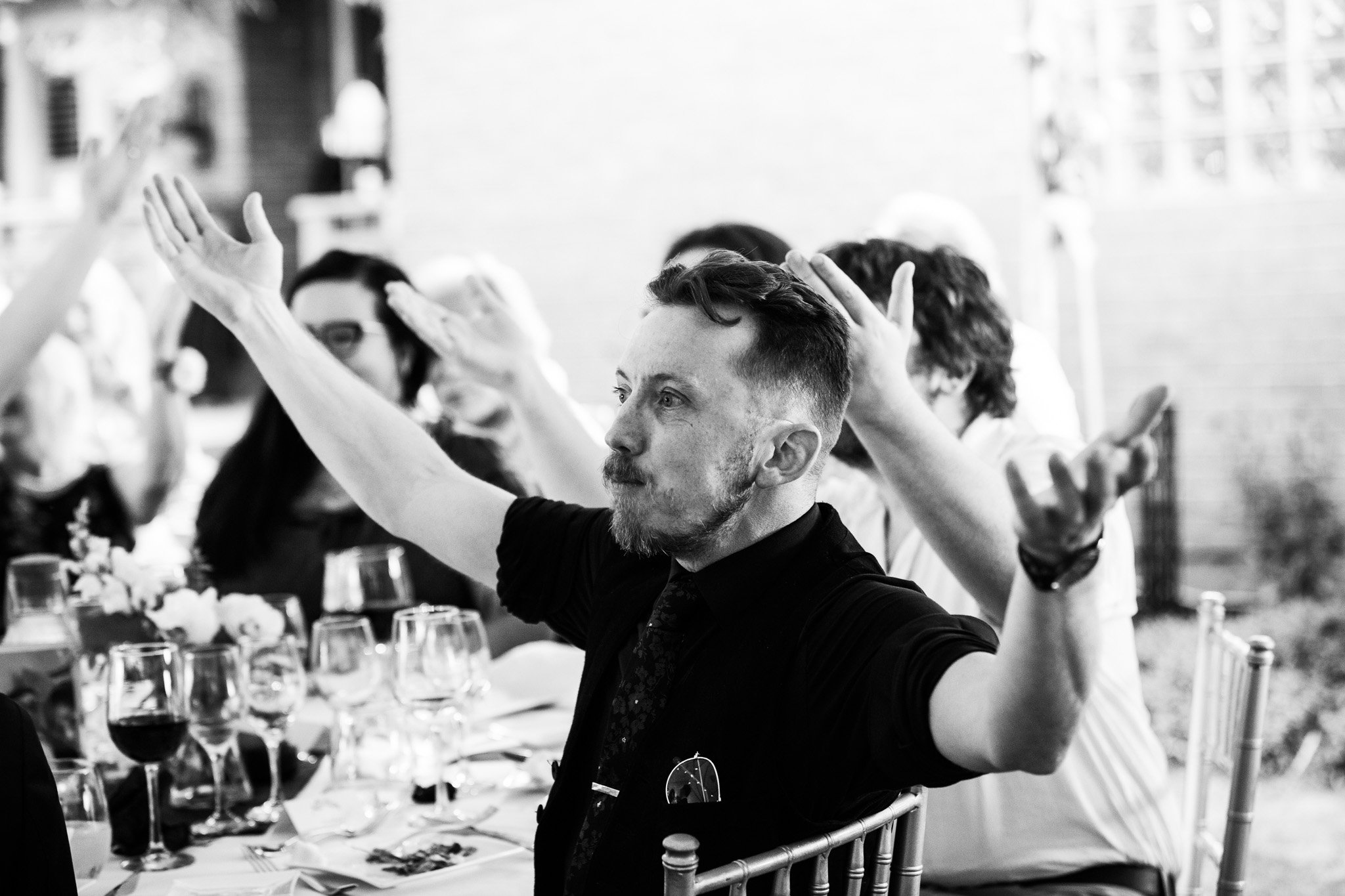 wedding guest gesturing arms wide during wedding reception - black and white wedding photography.jpg