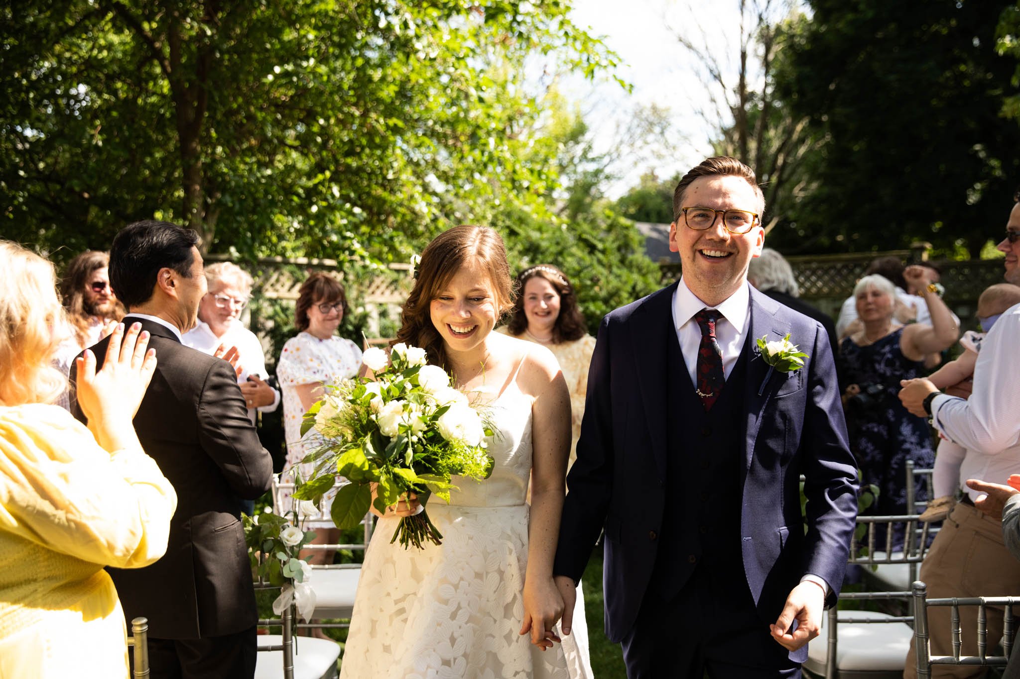 bride and groom walking up aisle holding hands in backyard wedding.jpg