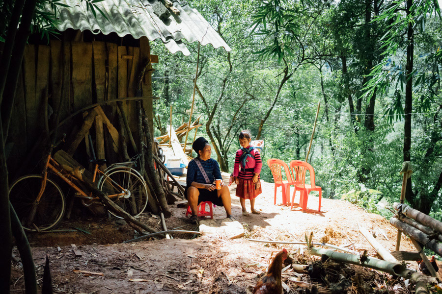 Pế’s mother Mai in front of their house.
