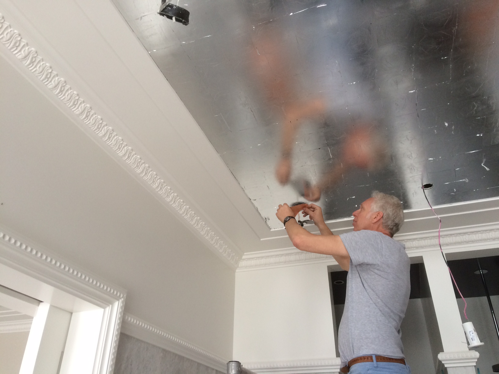 Silver leafing a ceiling in process .