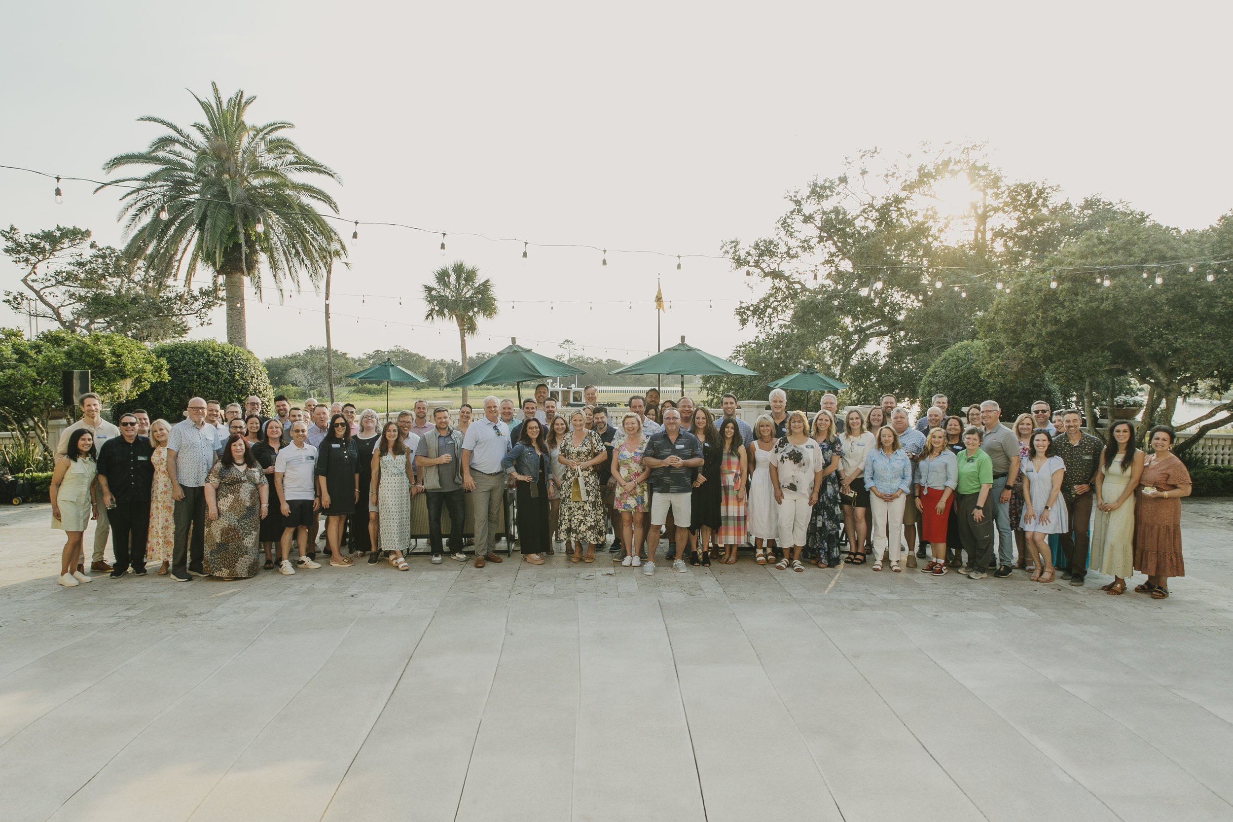 Group photo of the whole Swiss Re producer conference on the Sea Island terrace at sunset