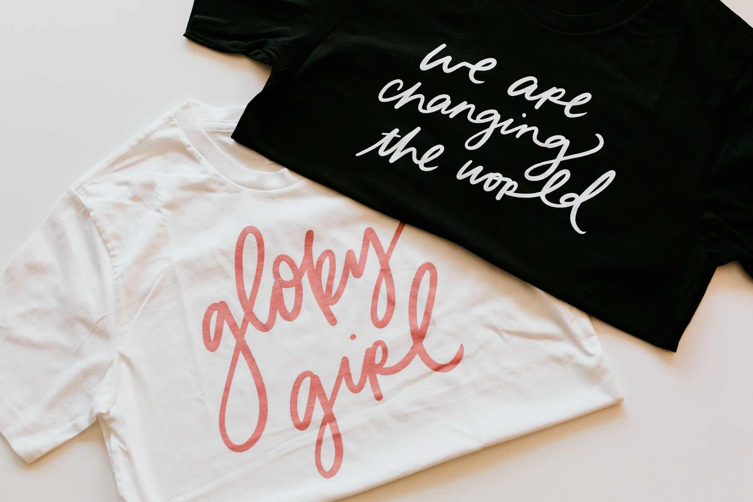 Glory Girl and We Are Changing the World t shirts styled flat lay for a faith based apparel brand shoot