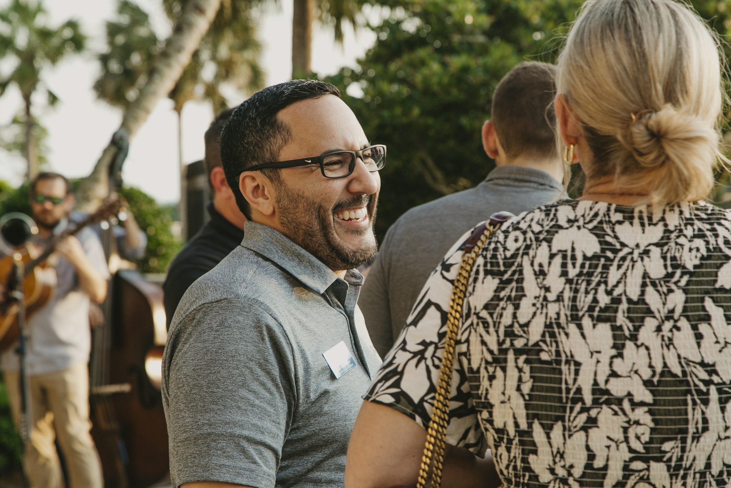Conference attendee laughing with friends at an outdoor evening reception at Sea Island while the band plays