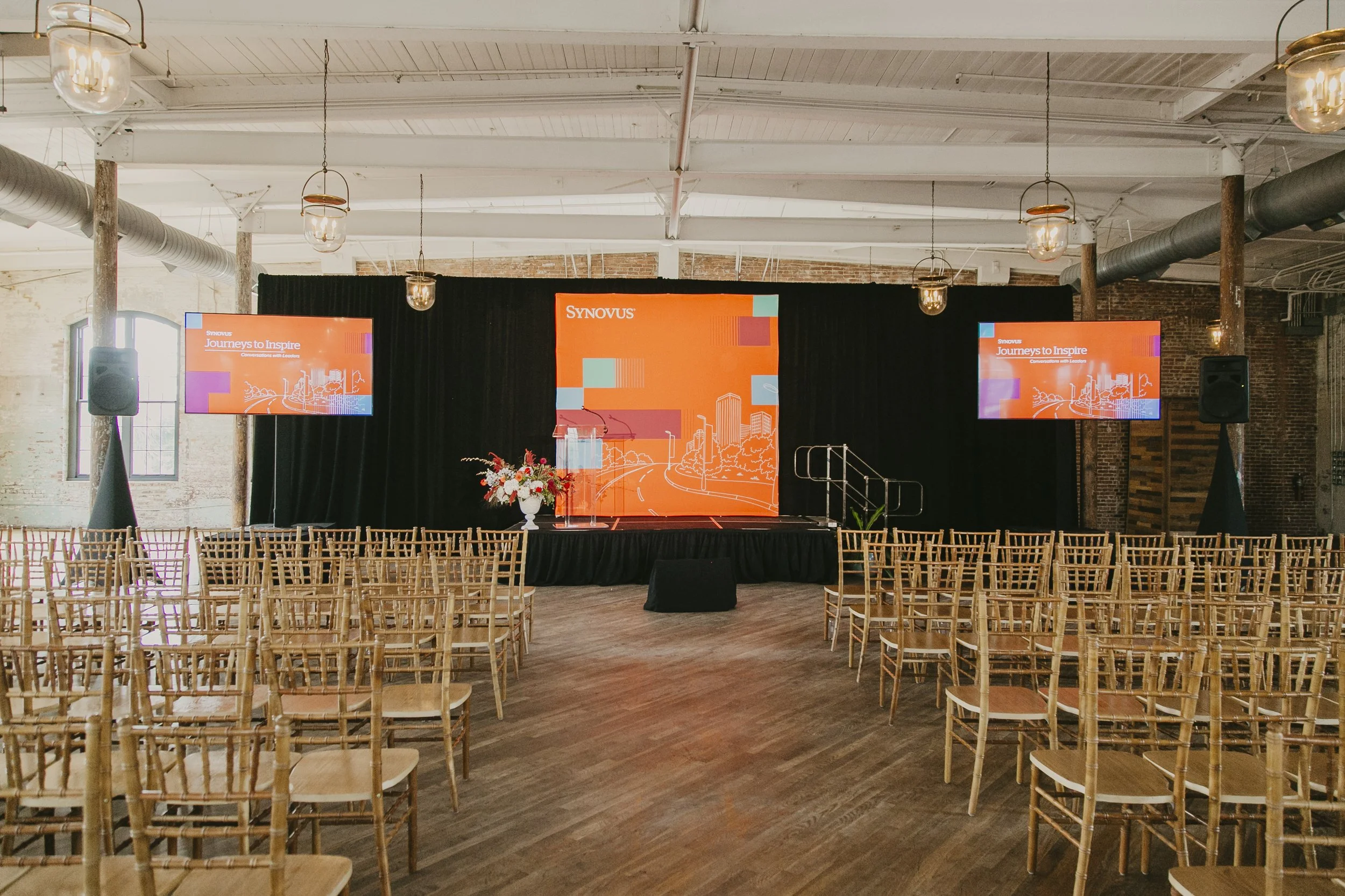 Stage and rows of gold chiavari chairs set before guests arrive for a corporate speaker event