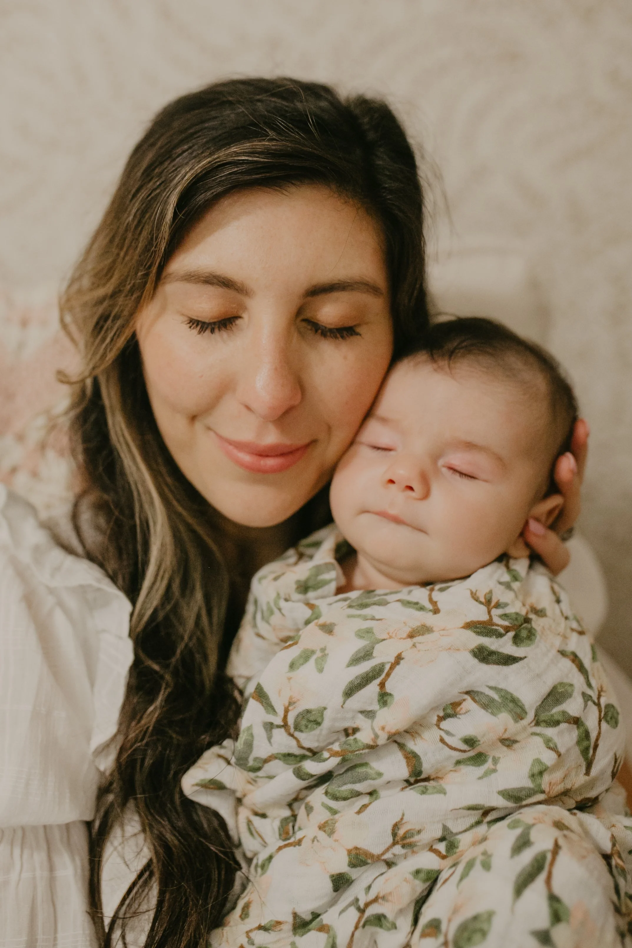 Mom holding her sleeping newborn cheek to cheek during an in-home newborn photography session in Charleston