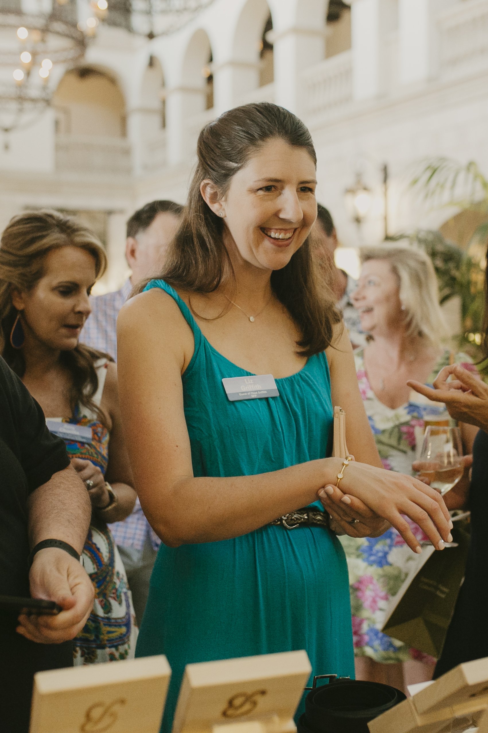 Conference attendee in a teal dress laughing with colleagues during a networking reception at Sea Island