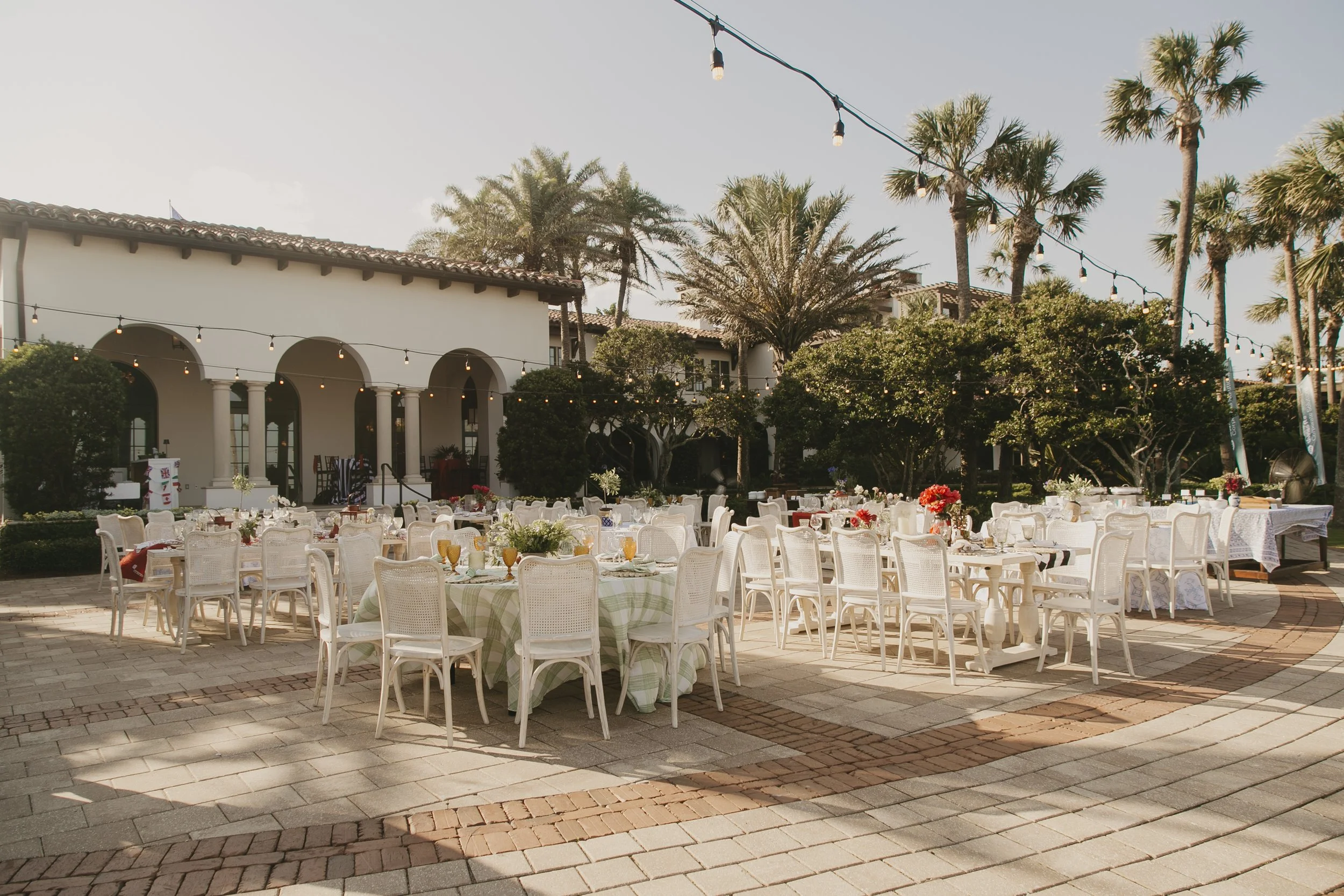Outdoor dinner tables set under string lights and palms on the Beach Club terrace at Sea Island Resort