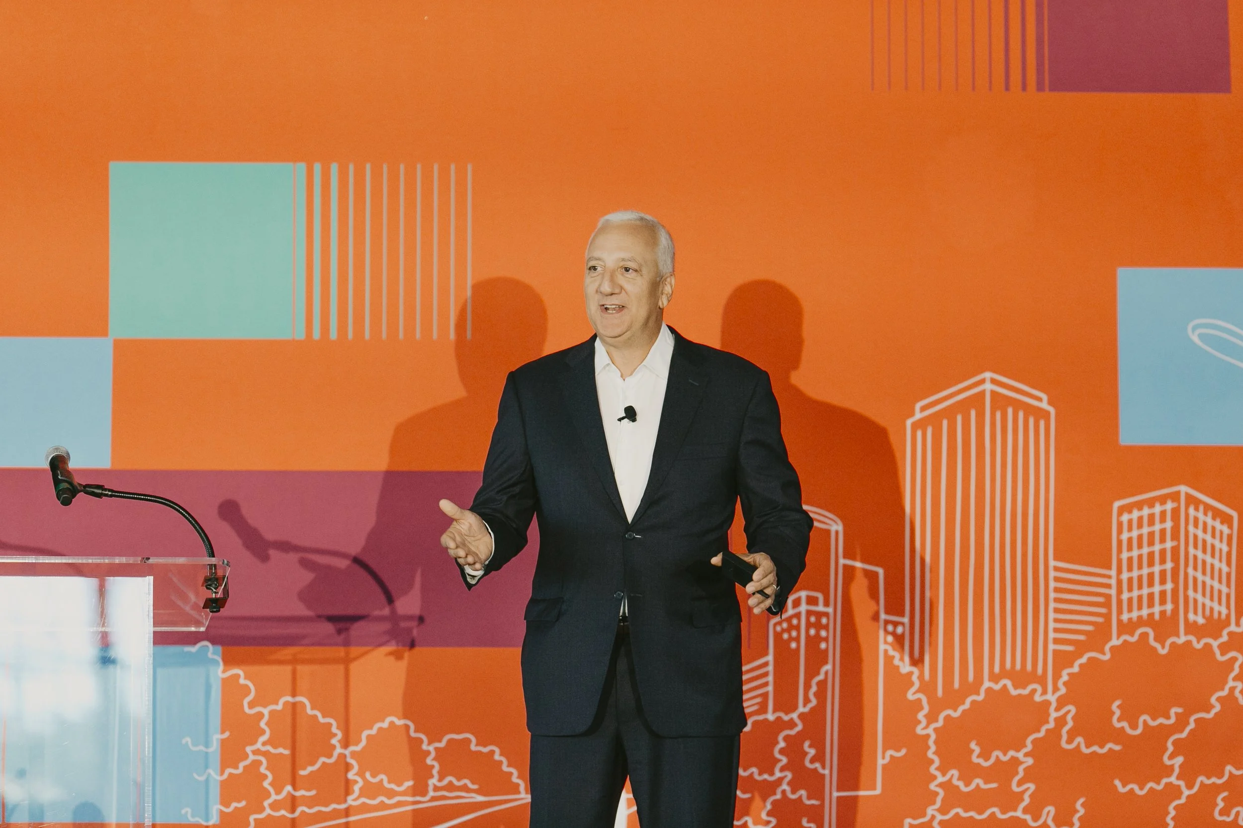 Keynote speaker on stage in front of the bright orange Synovus backdrop at a corporate speaker series