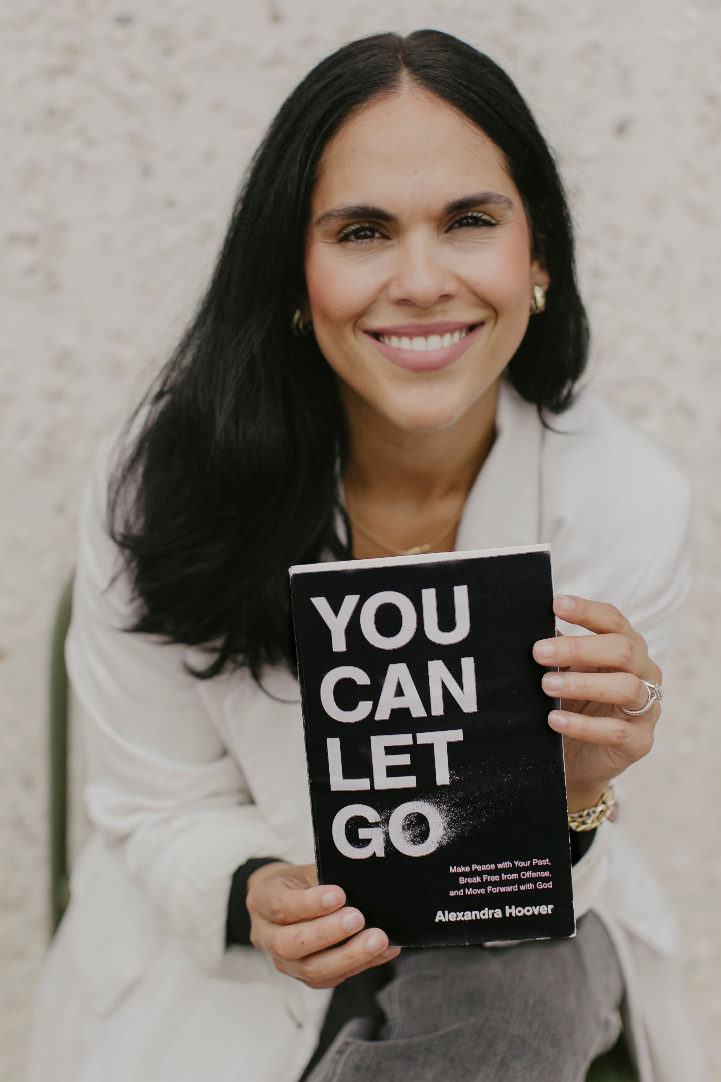Christian author Alexandra Hoover smiling and holding her book You Can Let Go during a branding session