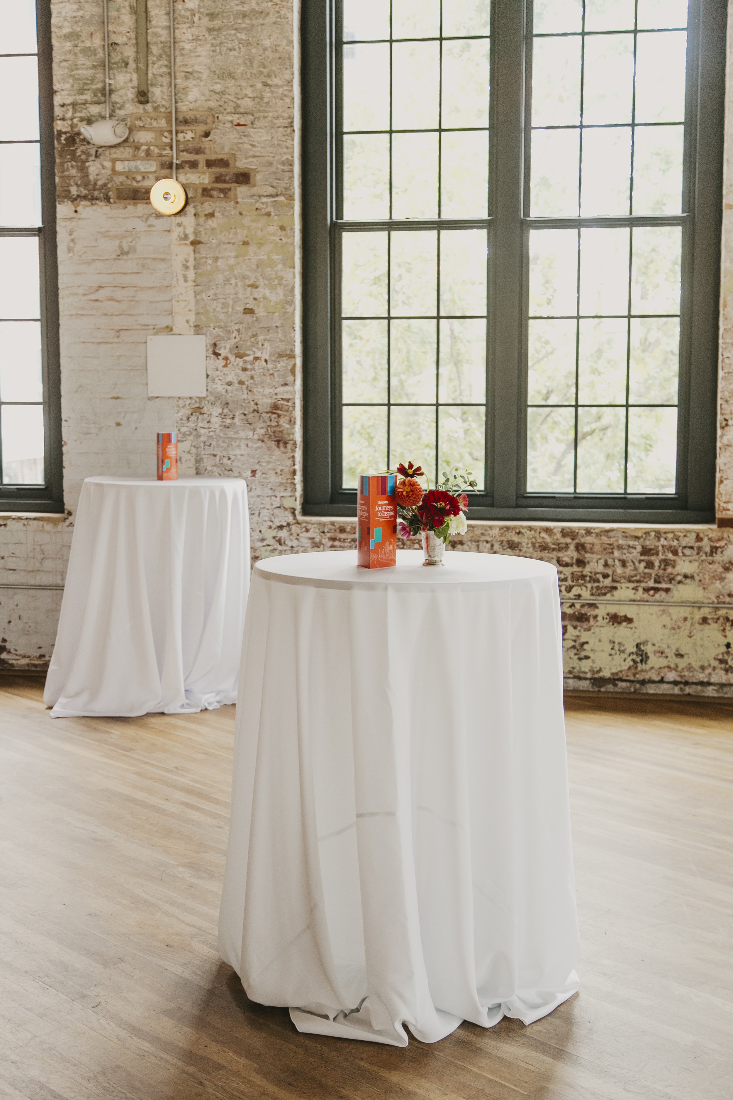Linen draped cocktail tables with centerpieces in a historic brick mill event venue