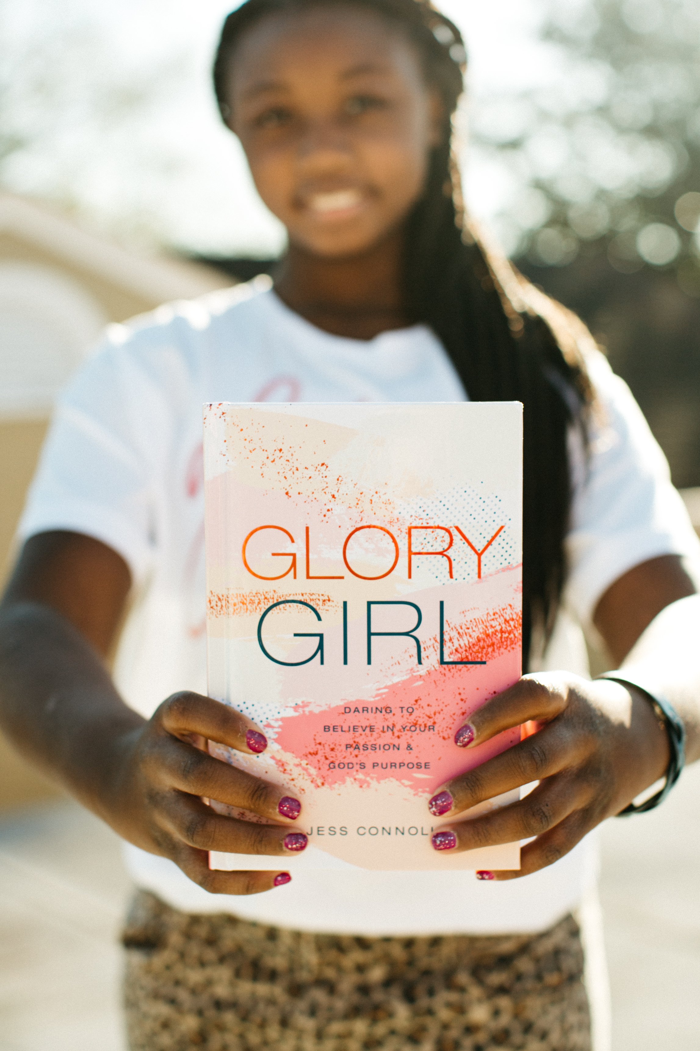 Young girl holding up the Glory Girl book during a brand and product photo session
