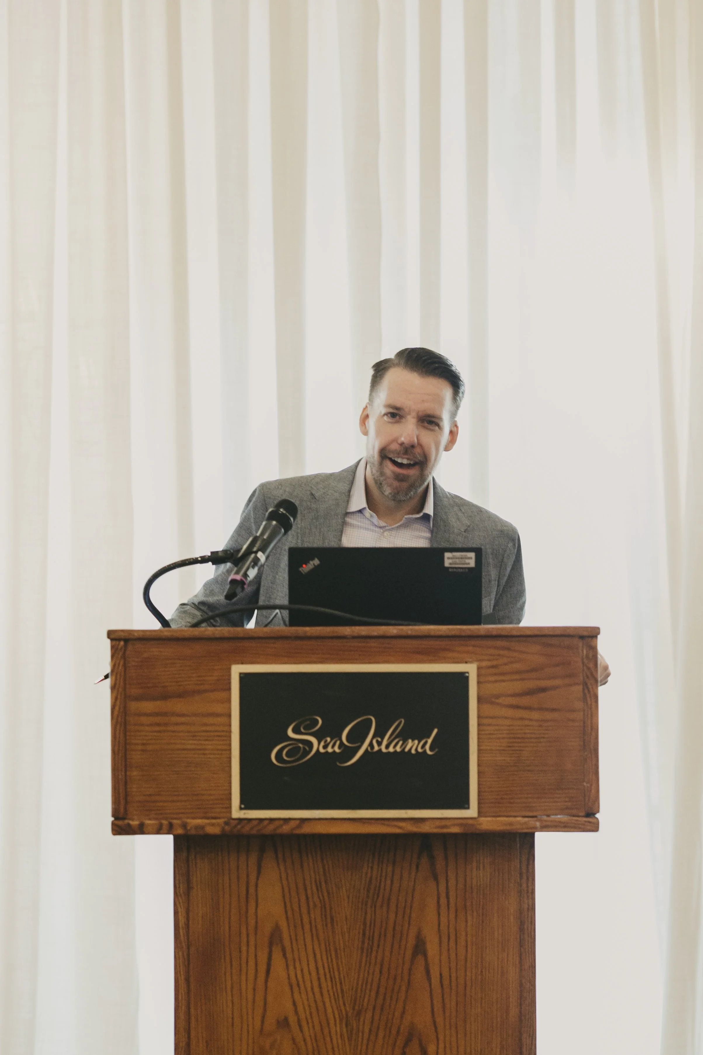Speaker presenting at a Sea Island podium during the Swiss Re producer conference