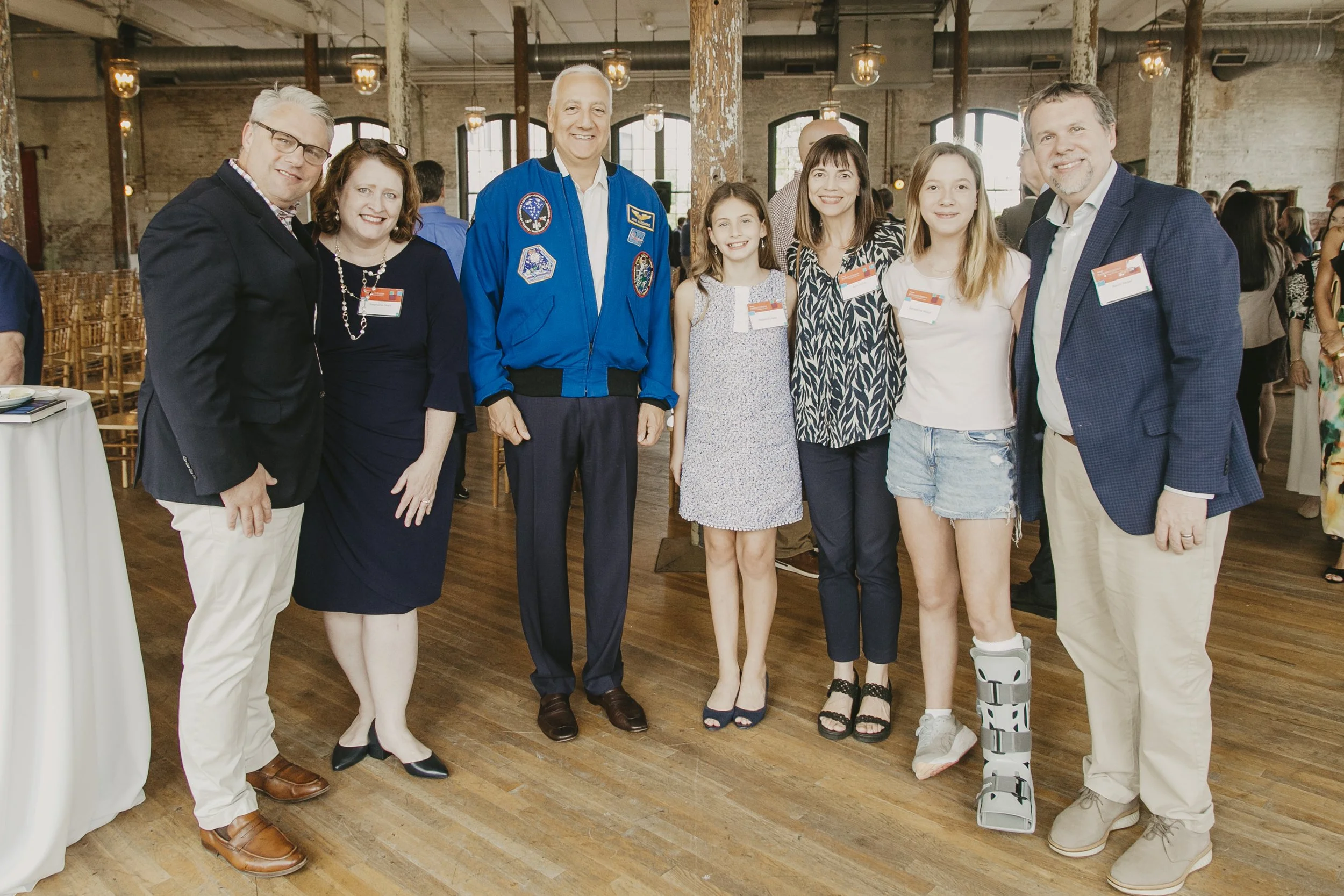 Guests posing with a NASA astronaut in his blue flight jacket at the Synovus Journeys to Inspire event