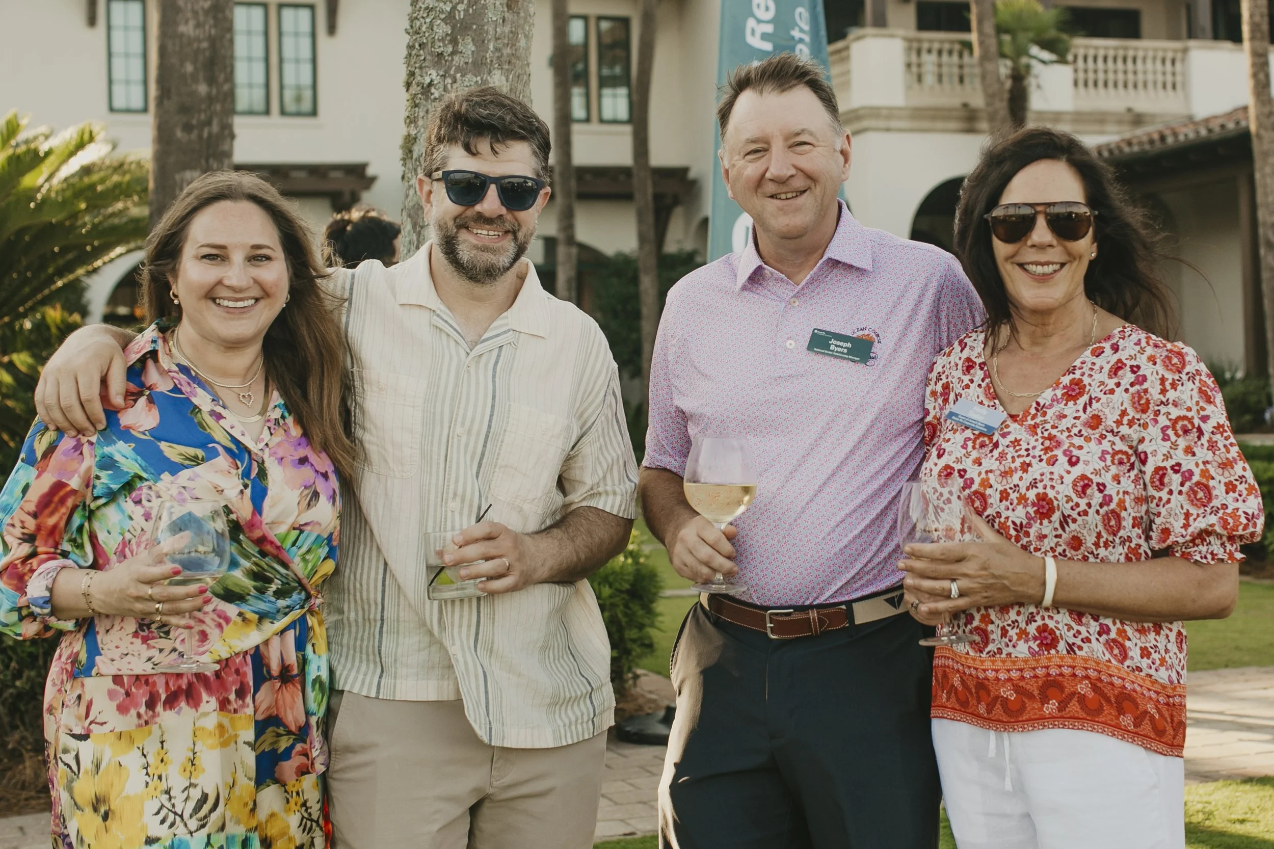 Two couples smiling with drinks at an outdoor conference reception at Sea Island Resort