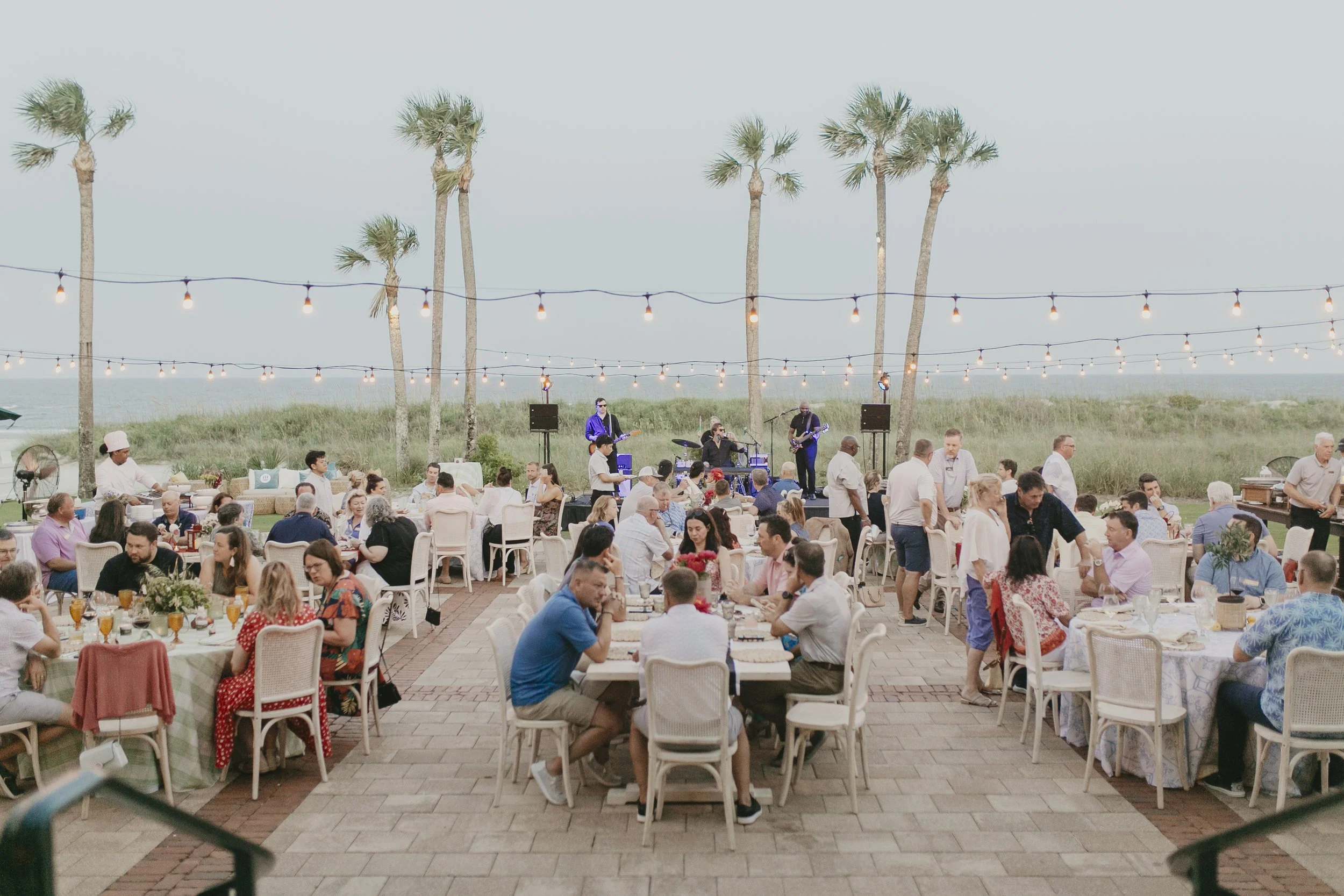 Oceanfront conference dinner under string lights and palm trees at Sea Island Resort in Georgia