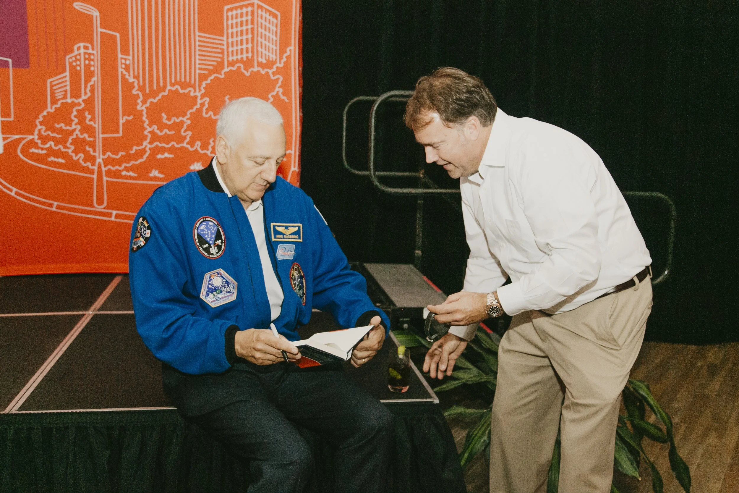 NASA astronaut signing a copy of his book for a guest at the Synovus Journeys to Inspire speaker event