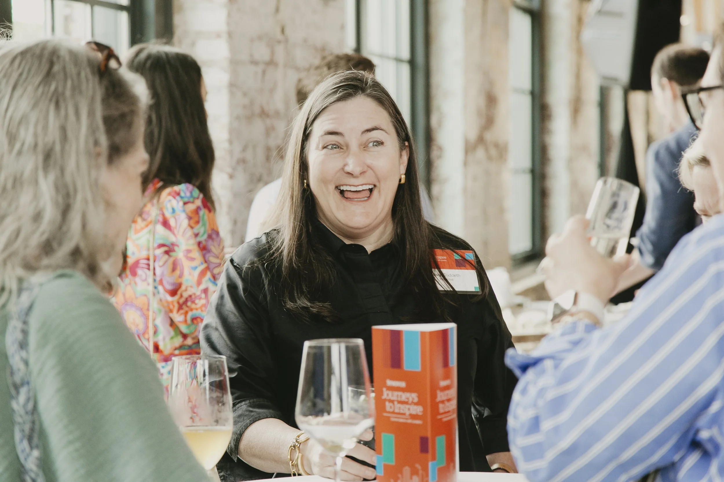 Attendee laughing at her table with the event program during the Synovus Journeys to Inspire reception
