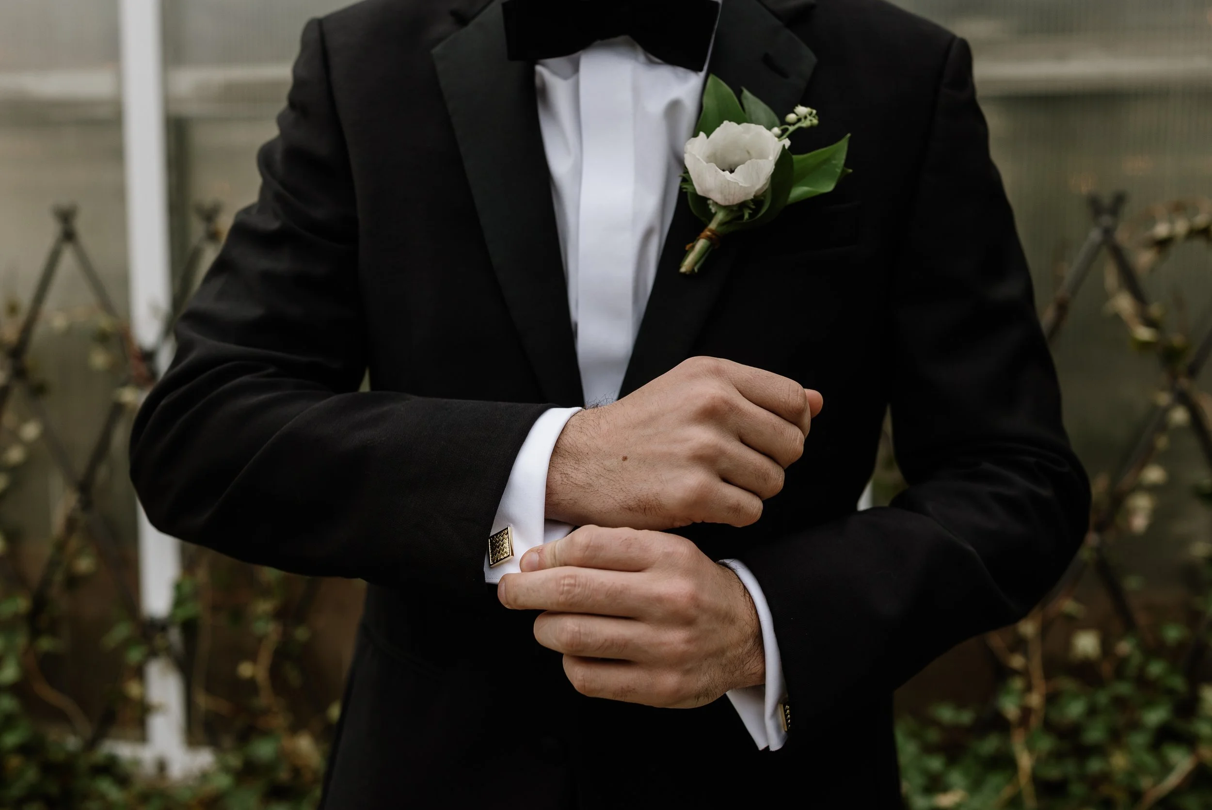 A bride and groom holding hands and smiling as they walk down the aisle at their wedding, surrounded by friends and family in an outdoor setting with lush greenery and floral decorations.