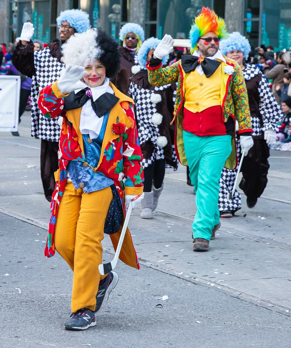  A clown waving to the crows carrying a hockey stick 