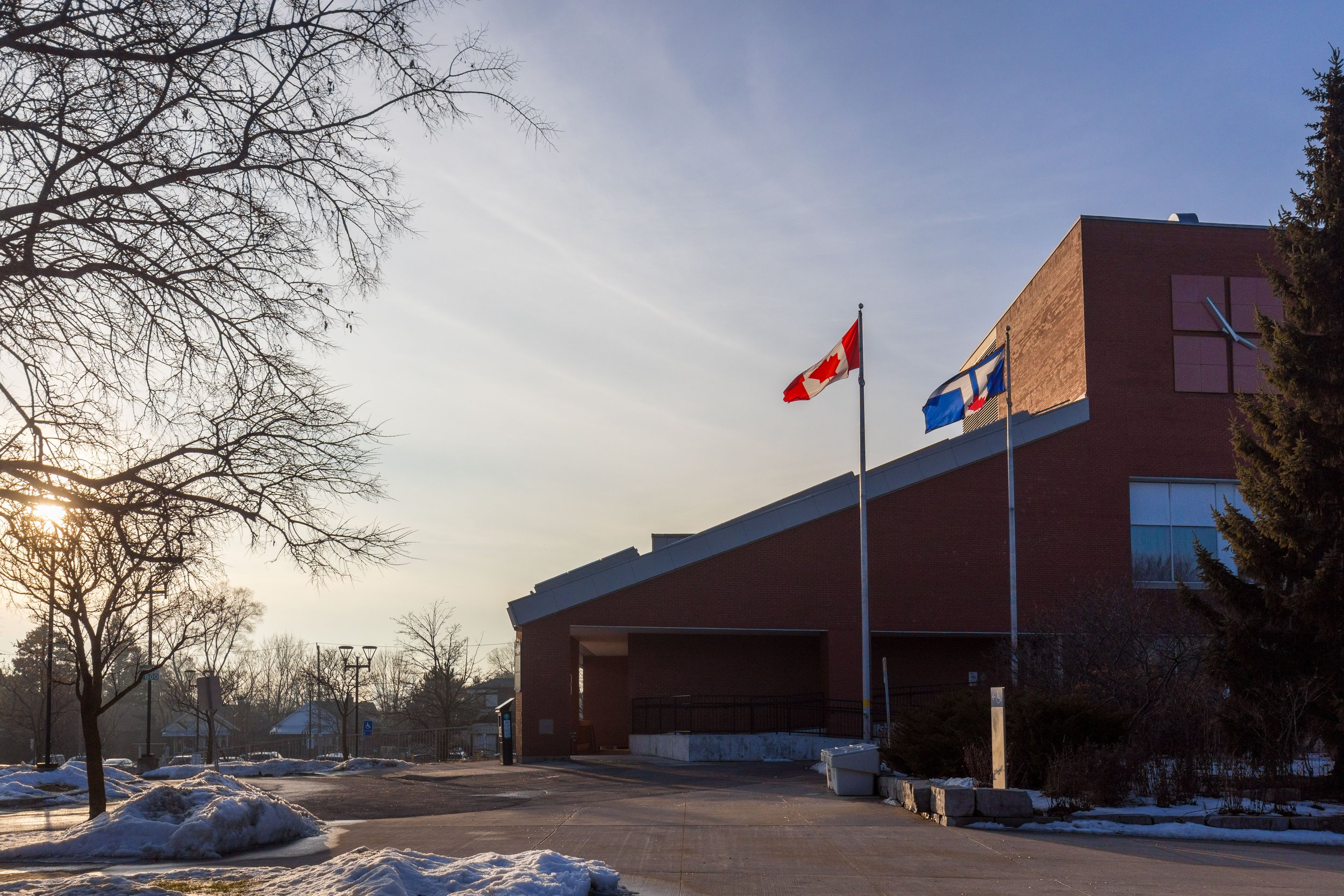 Canadian and City of Toronto flags flying outside East York Civic Centre on a winter afternoon