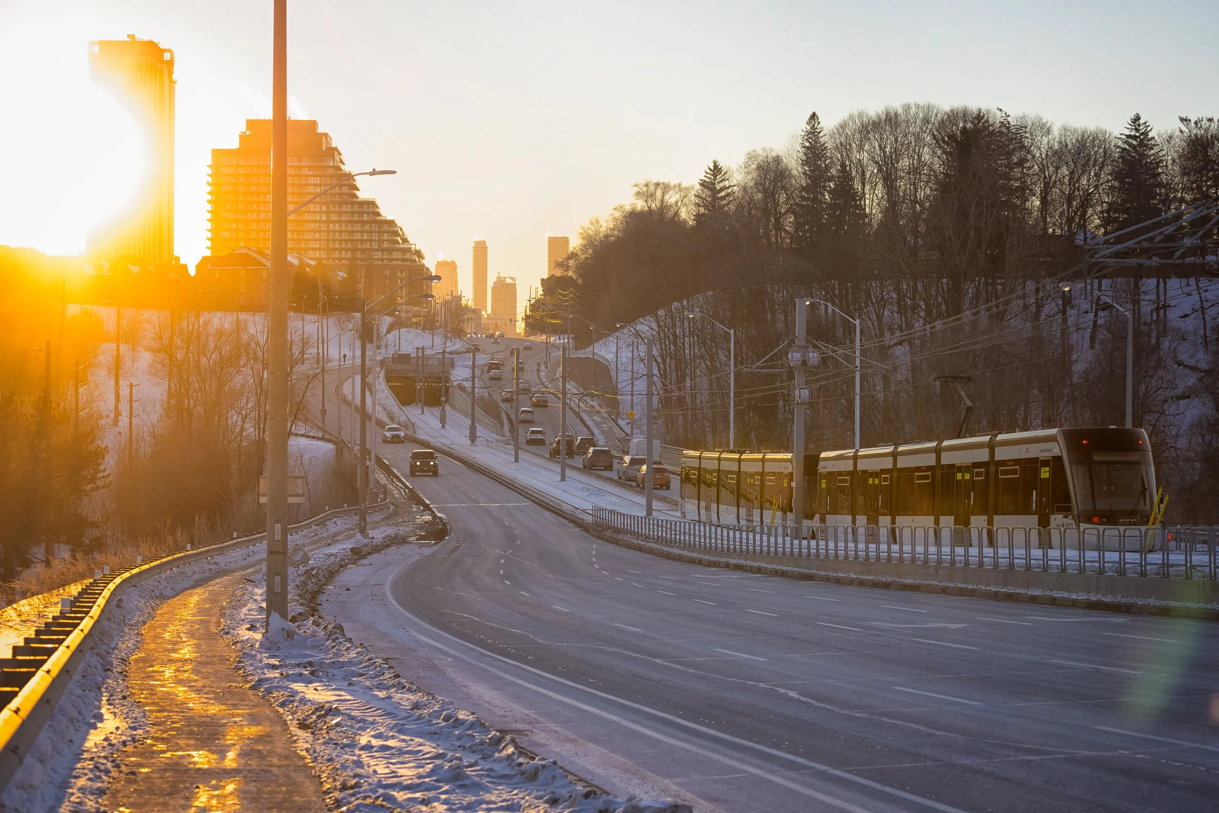  The low winter sun sets along the curve of Eglinton Avenue on the opening day of the Crosstown LRT, casting long light across the newly opened corridor at Sunnybrook Park Station. 