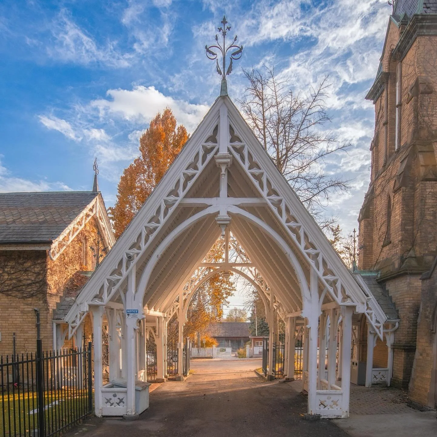 The old lychgate at the Toronto Necropolis glowing in late-autumn light &mdash; one of the quietest, most beautiful corners of the city.