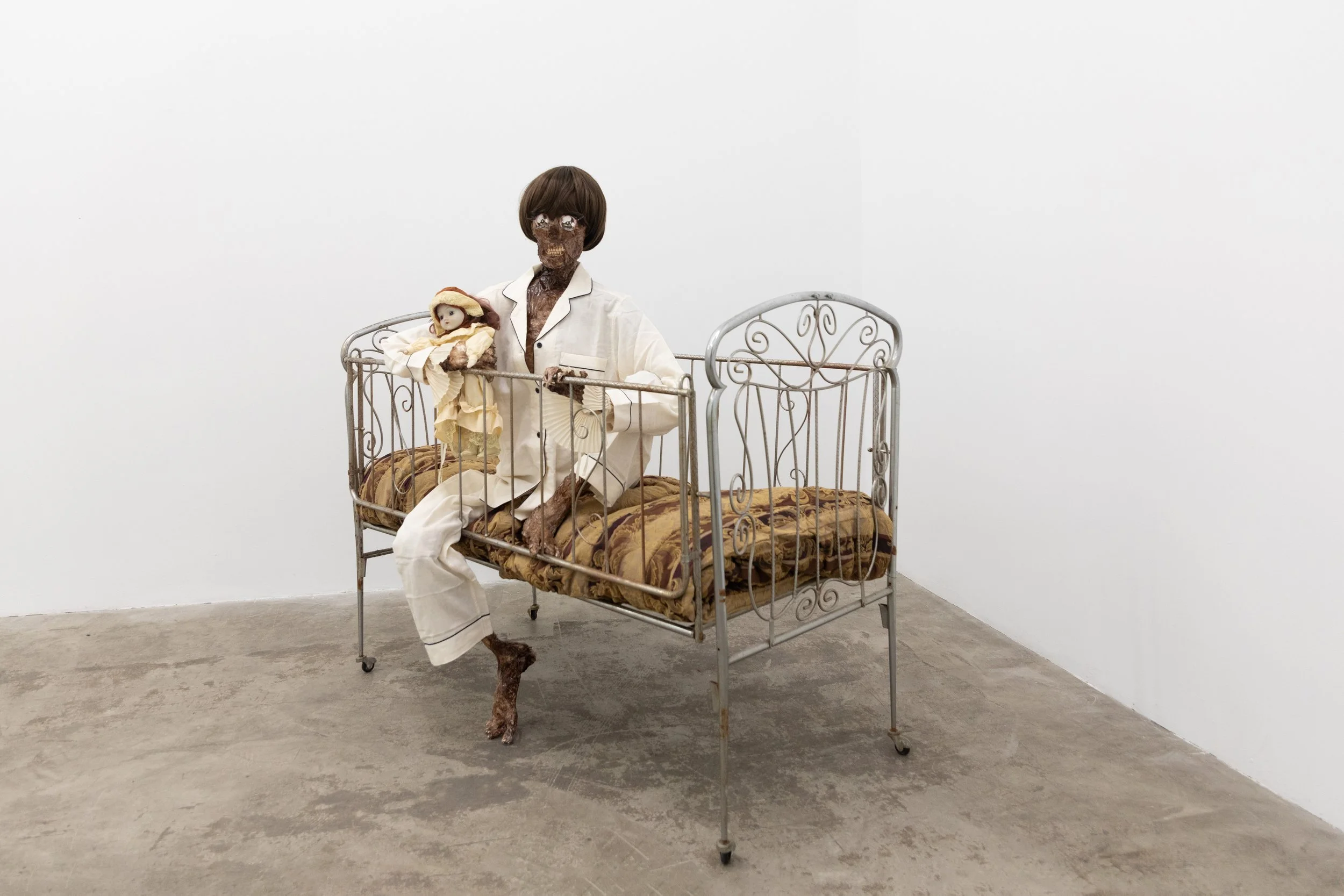  Growing up Gay Crib, comforter, plastic skeleton, melted drop cloth, wood stain, wig, acrylic paint on duralar, fake eyelashes, pyjama, and video game controller  Dimensions variable 2026 