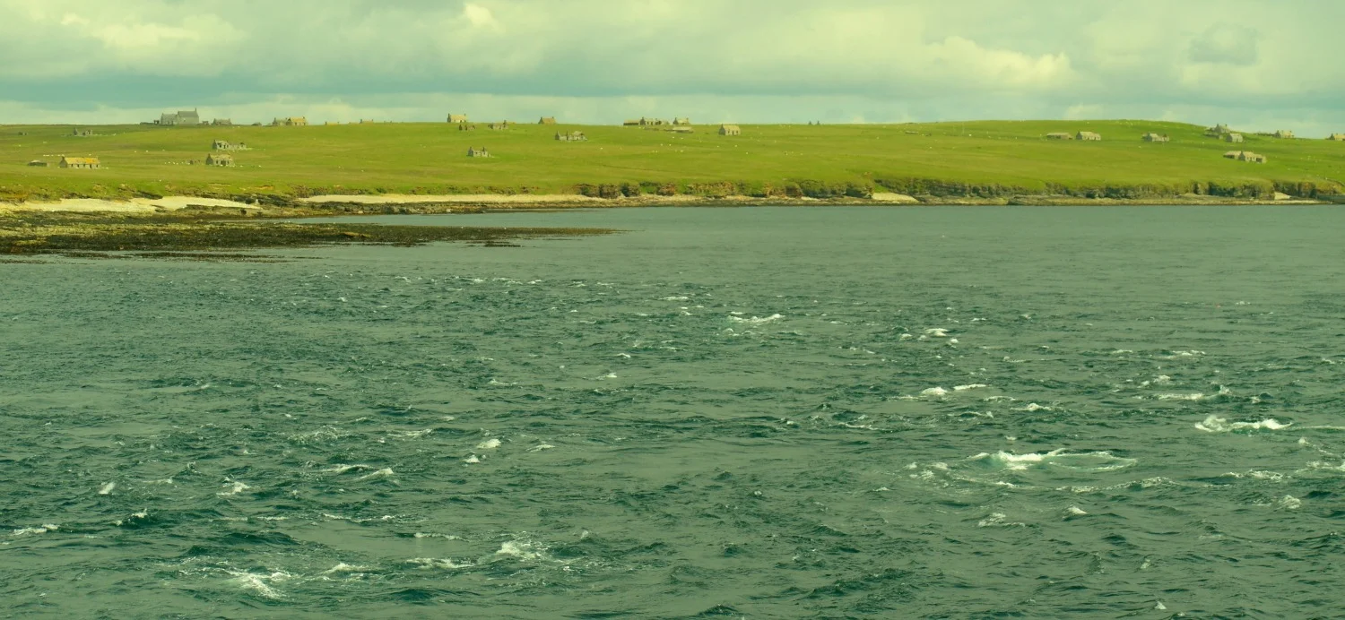 The deserted houses on the island of Stroma in the Pentland Firth, as well as the tide-race off its southern tip. This is a calm day.