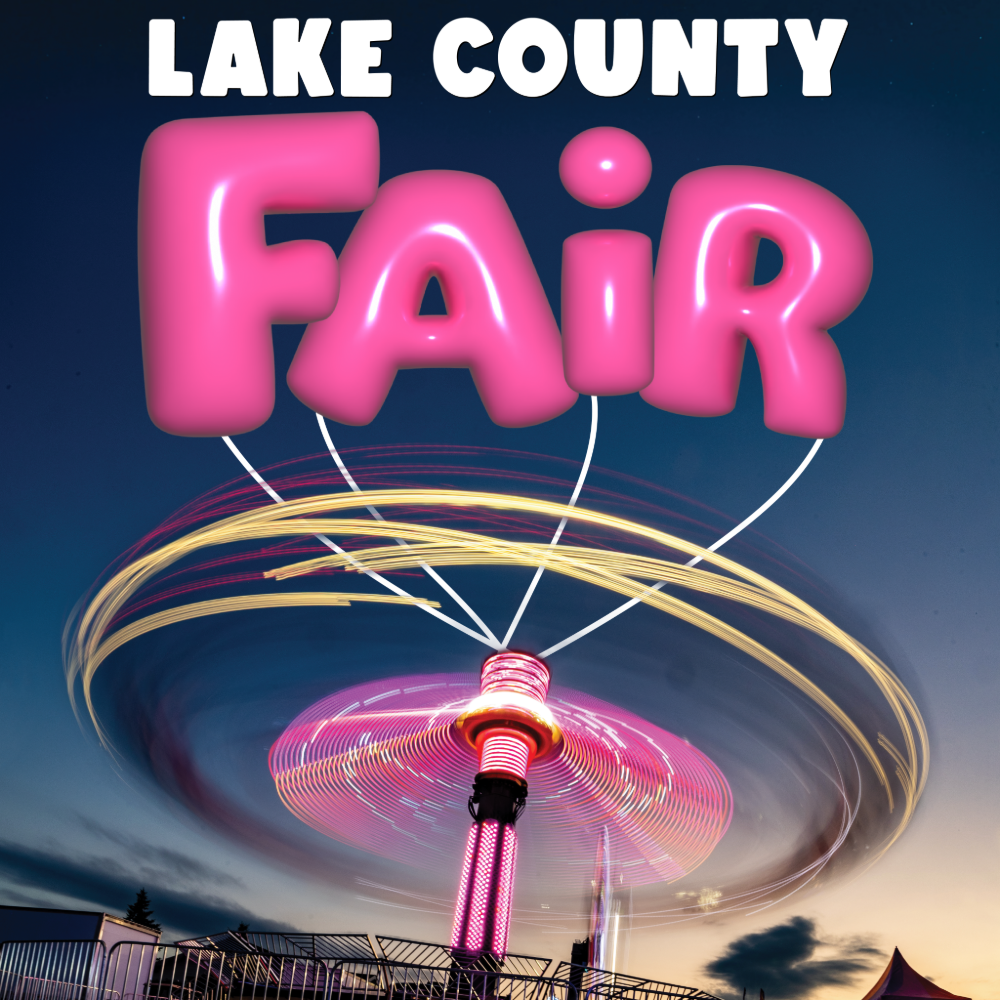 A spinning amusement park ride at dusk with pink balloons that spell out 'Fair' floating above it. The balloons are shaped like letters and are illuminated, with the night sky background.