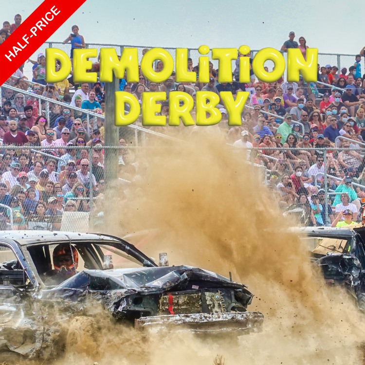 Two damaged cars participating in a demolition derby, with dust in the air and a large crowd of spectators in the background.