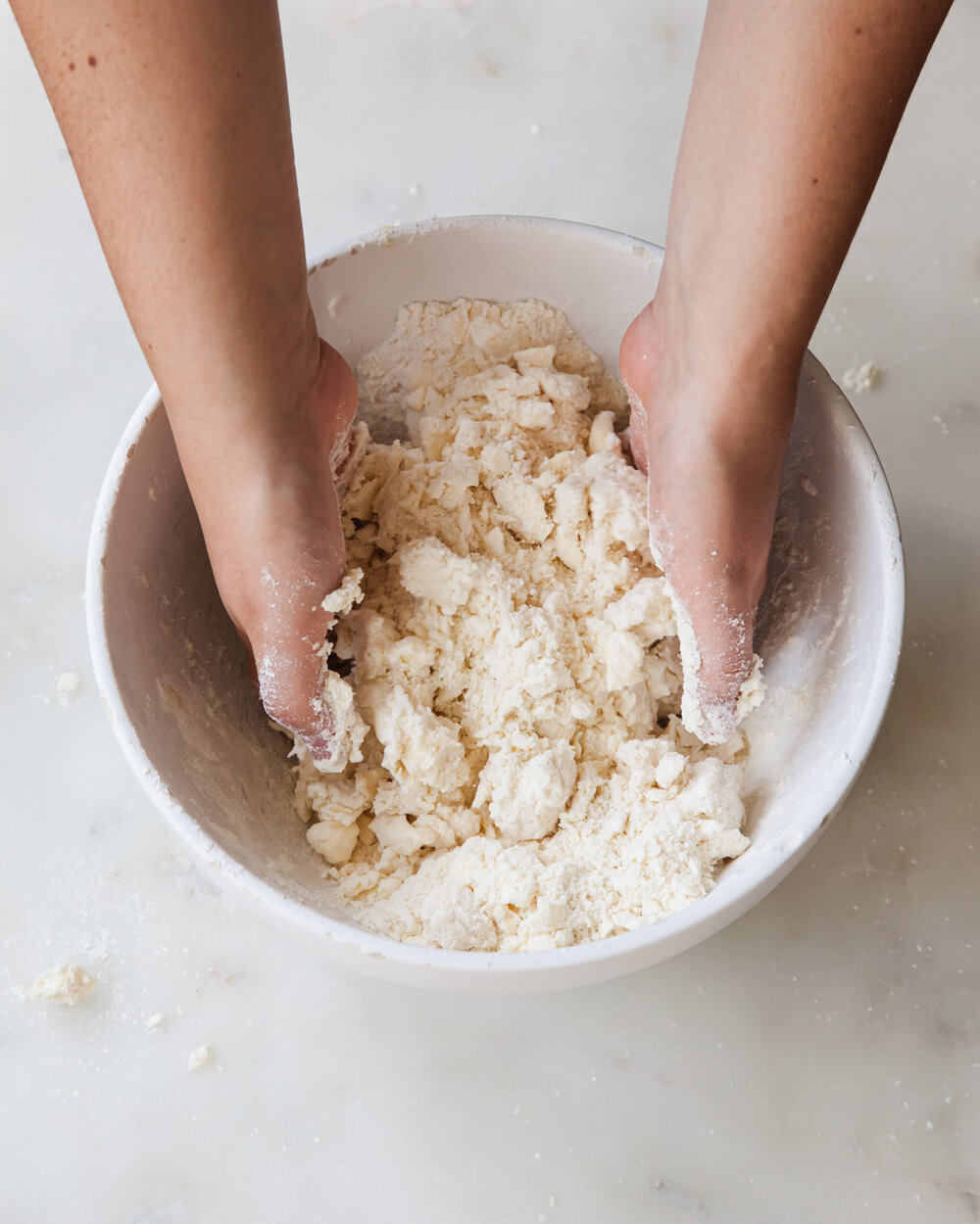 Immediately dip hands into the bottom of the bowl and start tossing the dough to integrate the water.